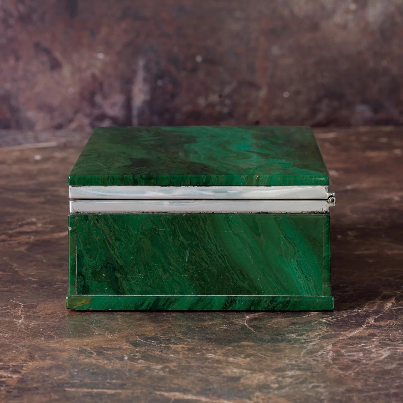 An exceptional box made from Malachite with leather covering to the base. Originally used as a cigarette box, a silver hinge and frame join the top and bottom sections. Made and retailed by Callow of Mount Street, London. Hallmarked London