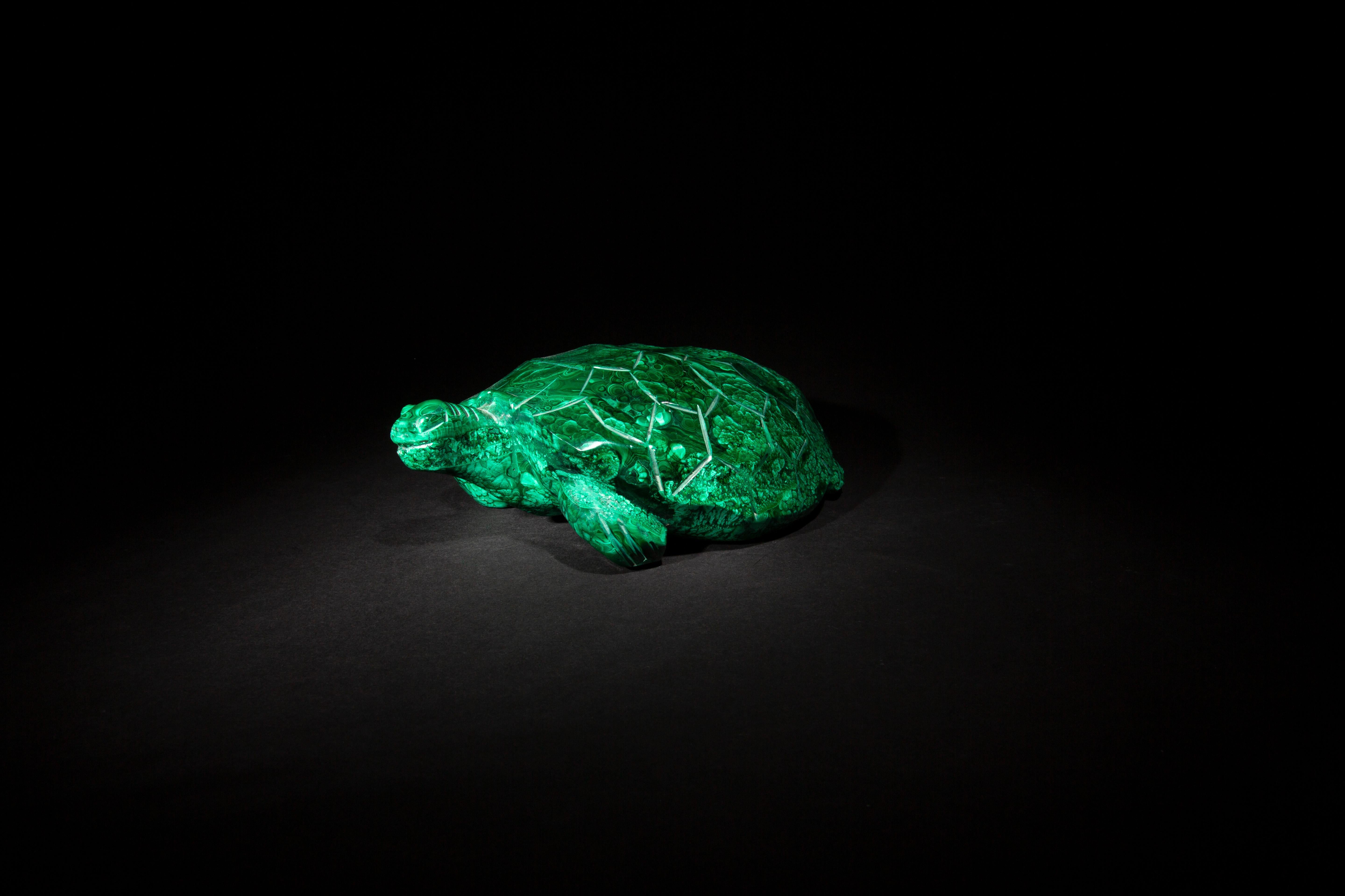 This elegant malachite turtle sculpture, measuring 8.5 inches by 6 inches by 2.75 inches, is a true gem of craftsmanship. Skillfully carved from premium malachite, it features the stone's signature vibrant green swirls and intricate patterns, which