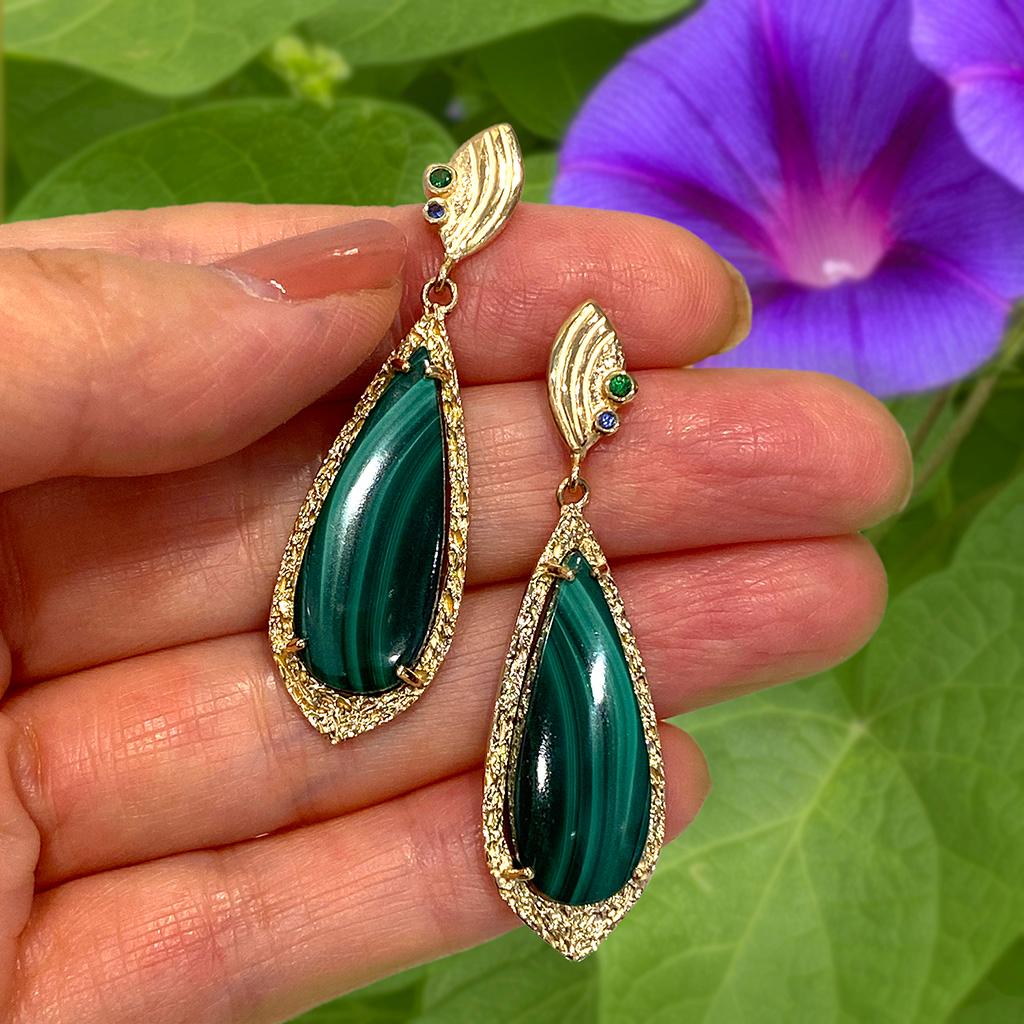 Keiko Mita's unique Verde Earrings are handmade from leaf patterned Malachite (22.86 Carats total weight) set in textured 14 Karat Yellow Gold frames and complemented with sparkling Green Garnets (0.04 total weight) and Blue Sapphires (0..02 Carats