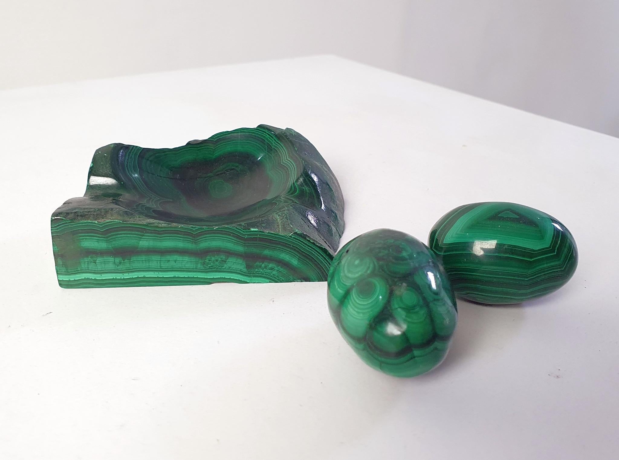 A set consisting of one natural solid vide poche (10x7x3 cm) of malachite with an organic shape as well as a pair of eggs which are solid too. The measurements of the eggs are 5x3,5 cm.