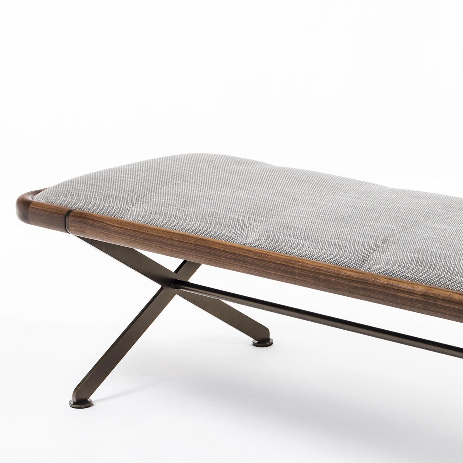 Banc Malanka avec structure d'assise en bois massif de noyer, 
rembourré et recouvert de tissu gris Cat. C. Avec base 
structure en métal finition bronze. Également disponible avec d'autres 
couleurs et finitions des tissus, sur demande.