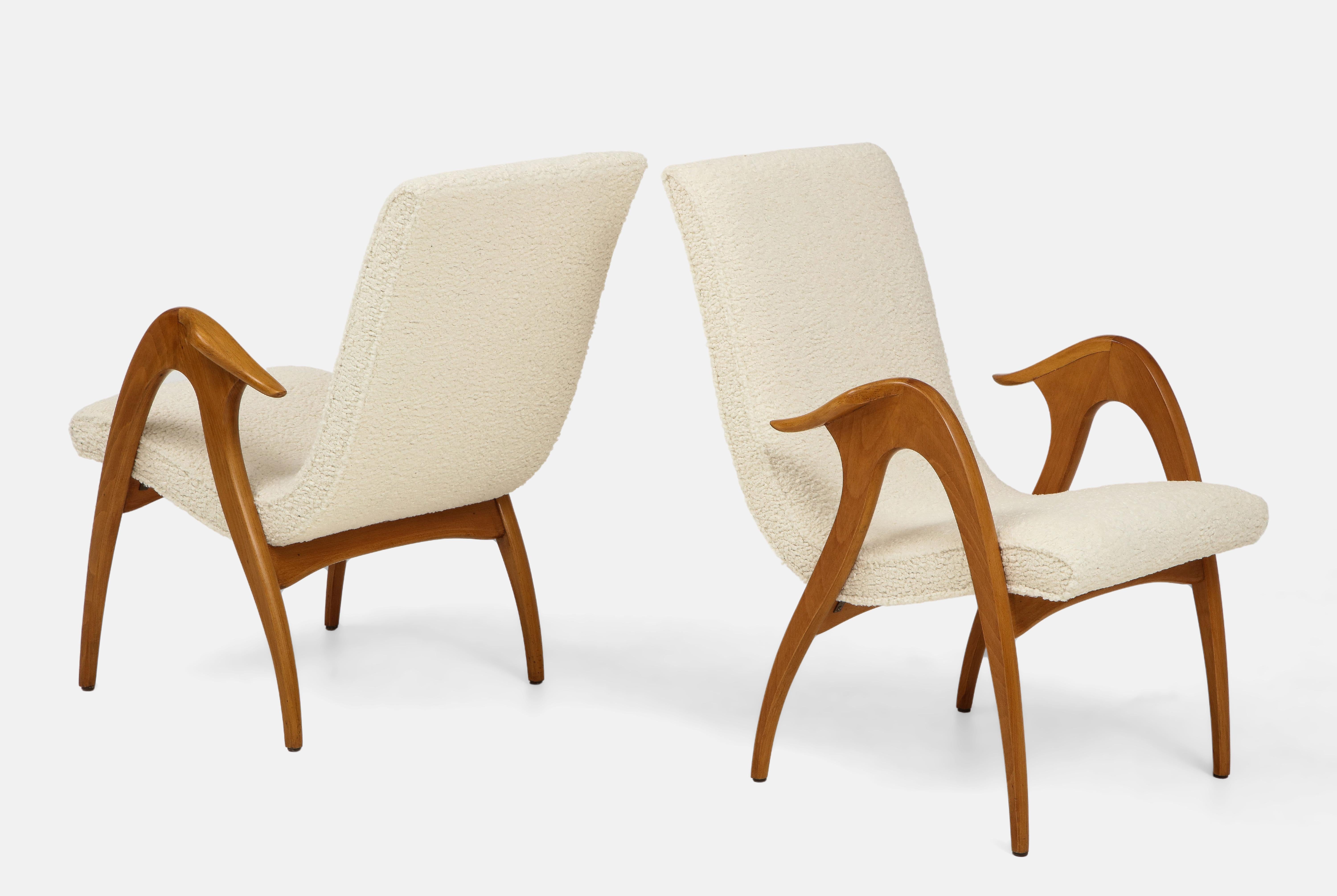 Malatesta and Mason pair of sculptural armchairs consisting of ivory bouclé upholstered curved high backs and seats and figural wood arms and legs. These organically sinuous armchairs exemplify the craftsmanship and originality of mid-century modern