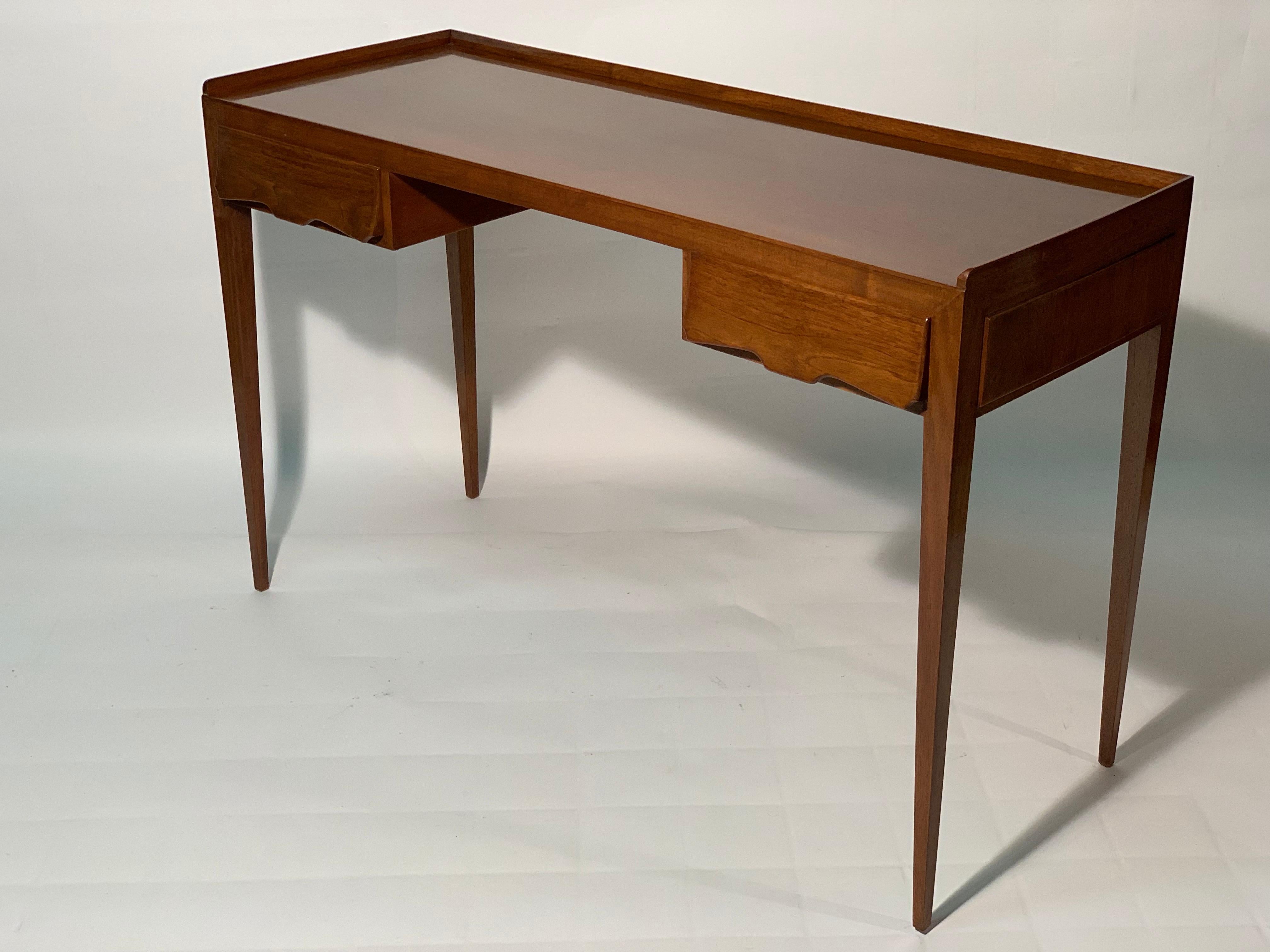 Elegant writing desk in natural walnut designed by the architect Paolo Malchiodi Firenze Italy at the end of the 1940's.
Four slender legs support a band with two shaped and sculpted drawers in solid walnut with a decoration handle.
This desk is
