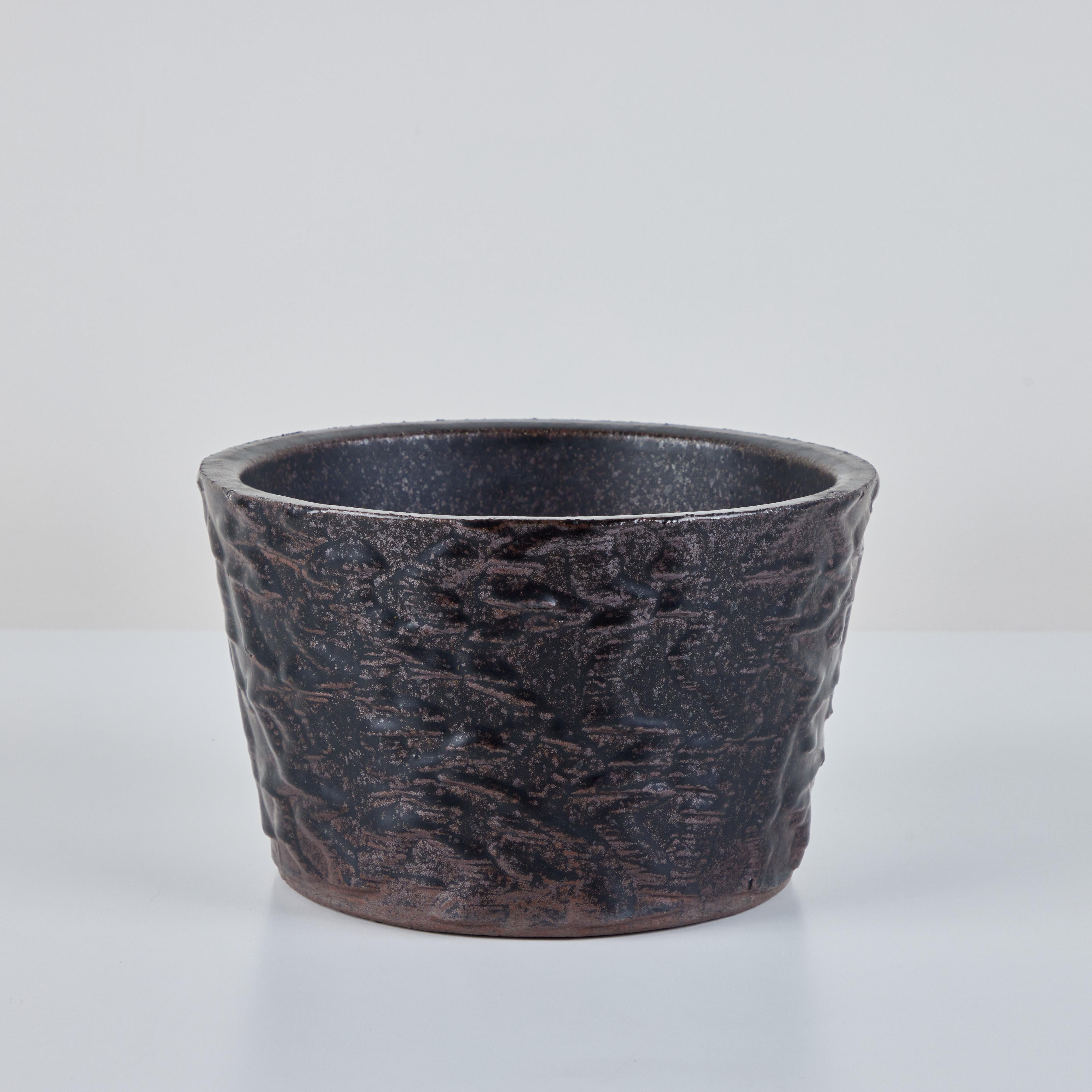 Malcom Leland Planter for Architectural Pottery, c.1960s, USA. This stoneware planter has a brown and black glazed exterior with texture as well as a glazed interior. The round planter tappers inwards slightly towards the bottom. 

Dimensions
9.75