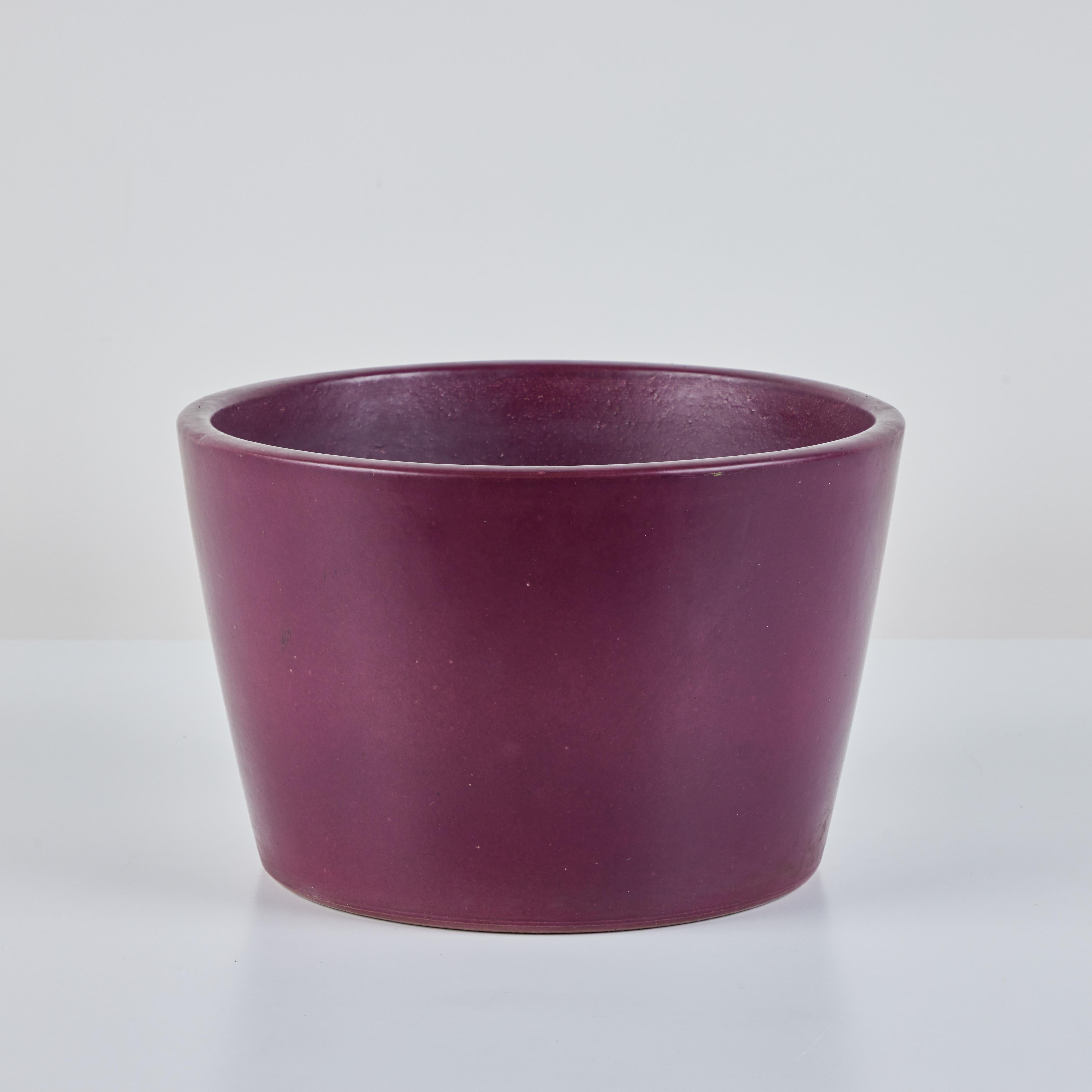 Malcom Leland Planter for Architectural Pottery, c.1960s, USA. This stoneware planter has a purple glazed exterior and interior. The round planter tappers inwards slightly towards the bottom. 

Dimensions
12.25