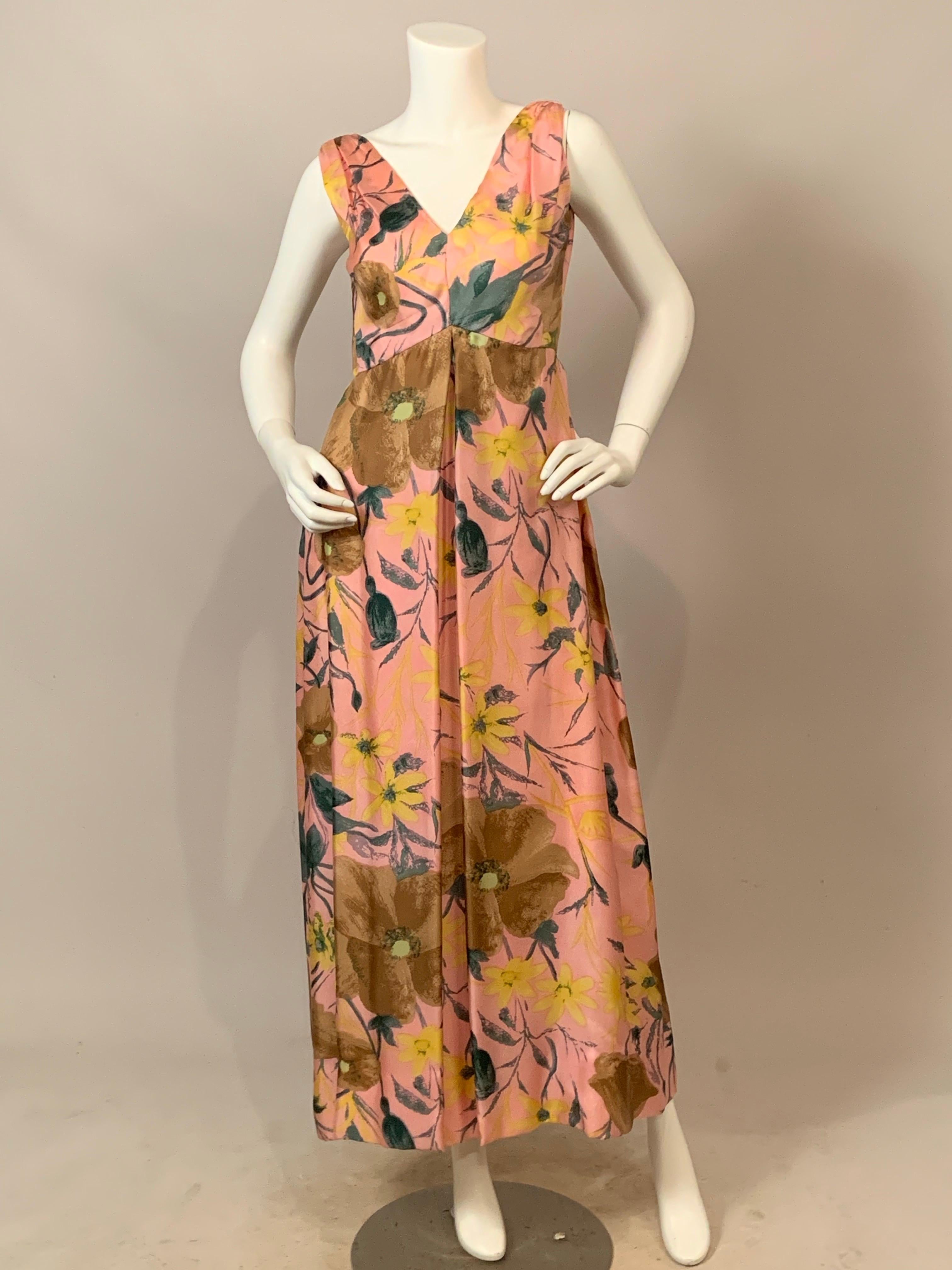 Dieses Abendkleid von Malcolm Starr aus rosafarbener Seide aus den 1960er Jahren hat ein florales Muster in Gelb-, Grün- und Brauntönen. Das ärmellose Kleid hat vorne und hinten einen tiefen V-Ausschnitt über einer erhöhten Taillenlinie. Der lange