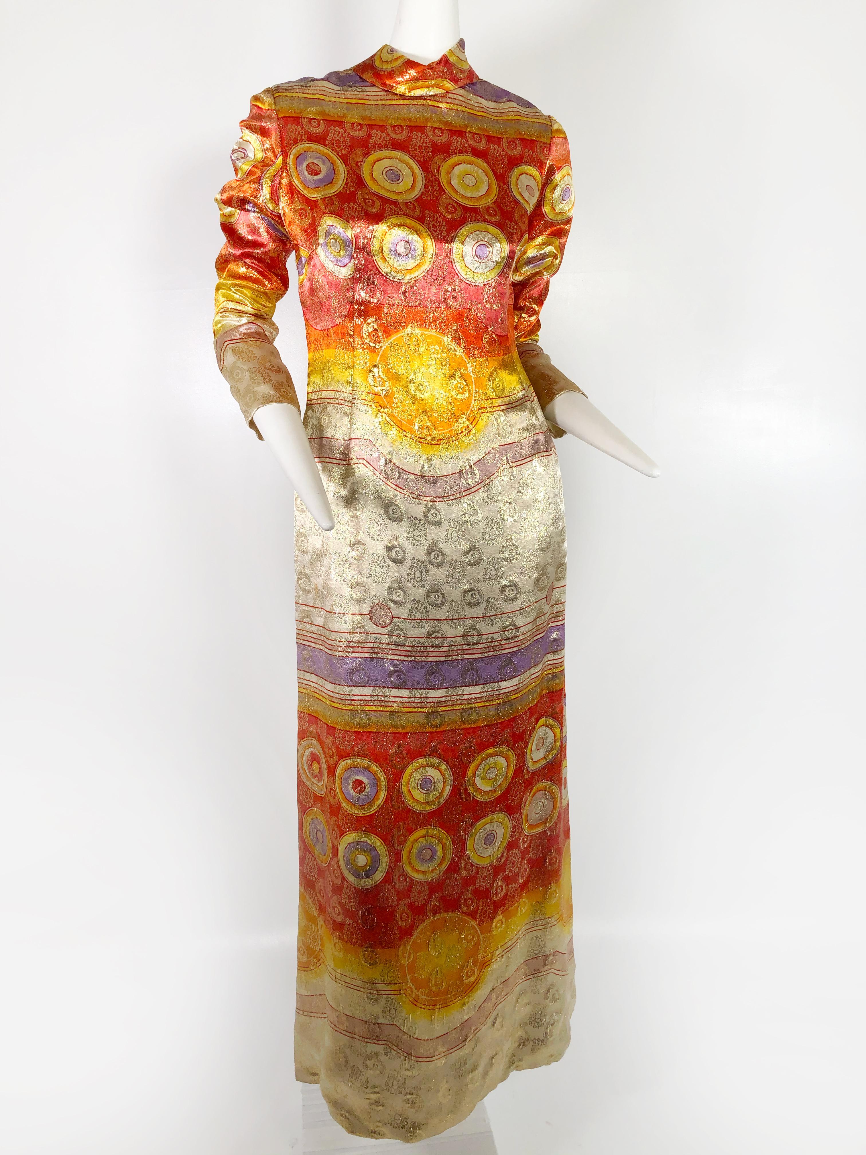 A 1960s Malcolm Starr lame maxi dress or gown with a groovy medallion pattern executed in orange, red, purple and white with metallics. With a banded collar and back zipper.  An easy fitted shift style.   