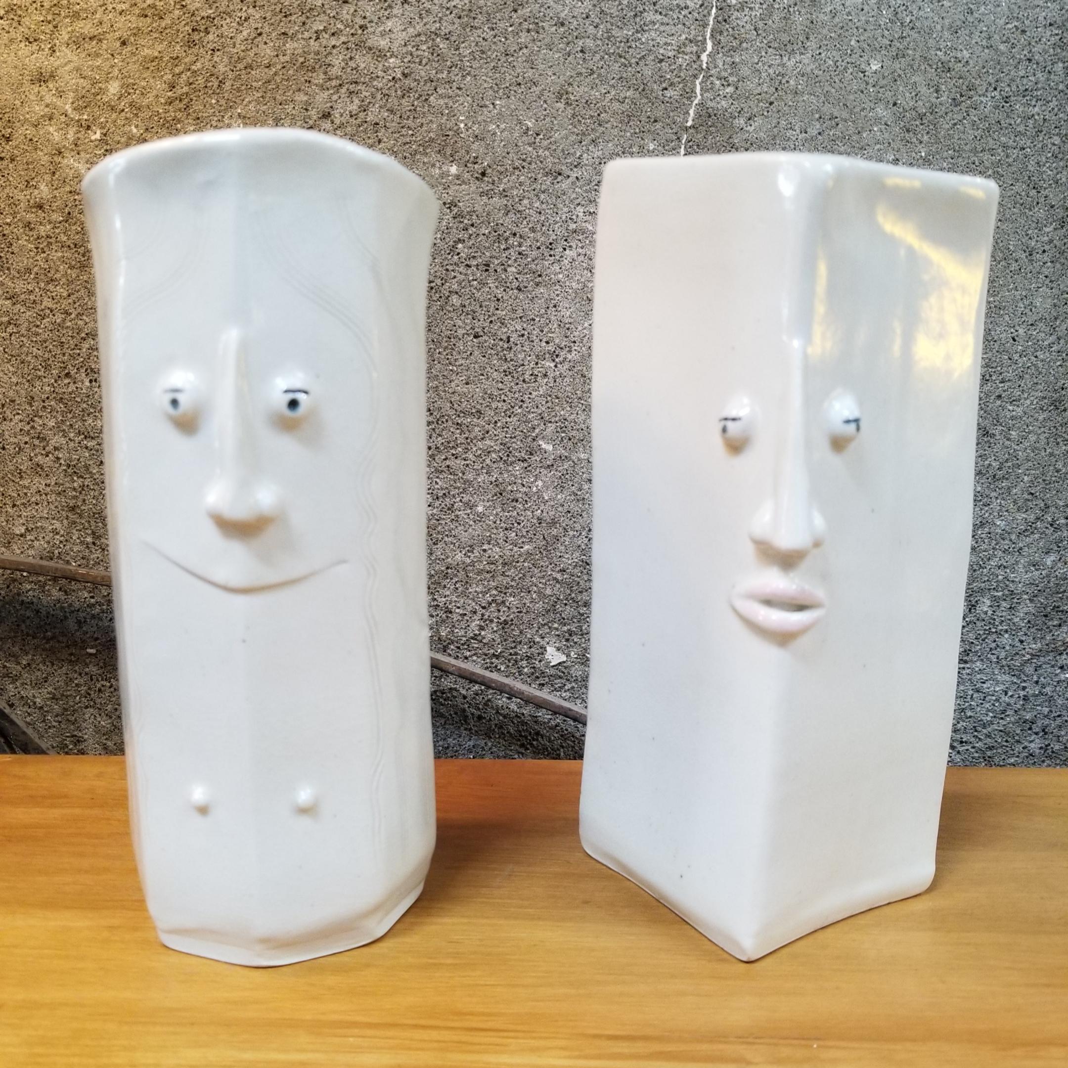 A pair of whimsical ceramic vases depicting a male and female face. Inscribed hair detail, facial features formed by hand. Unknown origin? Appear to be mid 20th century. In the manner of Bjorn Wiinblad. Unmarked, unsigned.
