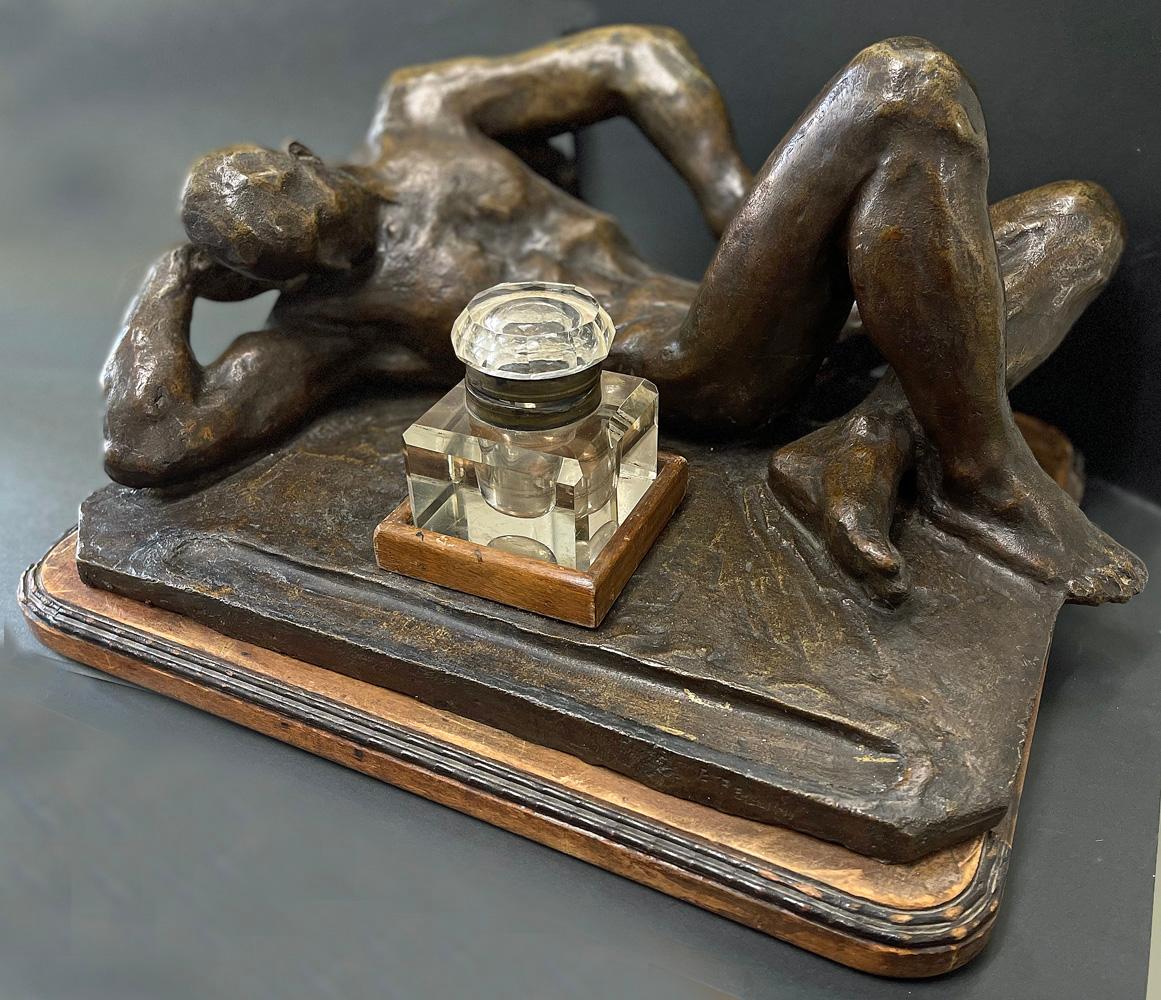 Created by one of Italy's premier sculptors of the early 20th century, Eugenio Pellini, this very large inkwell is dominated by a monumental male nude in repose, his head resting on one hand and his other arm laid to his side, all finished in a