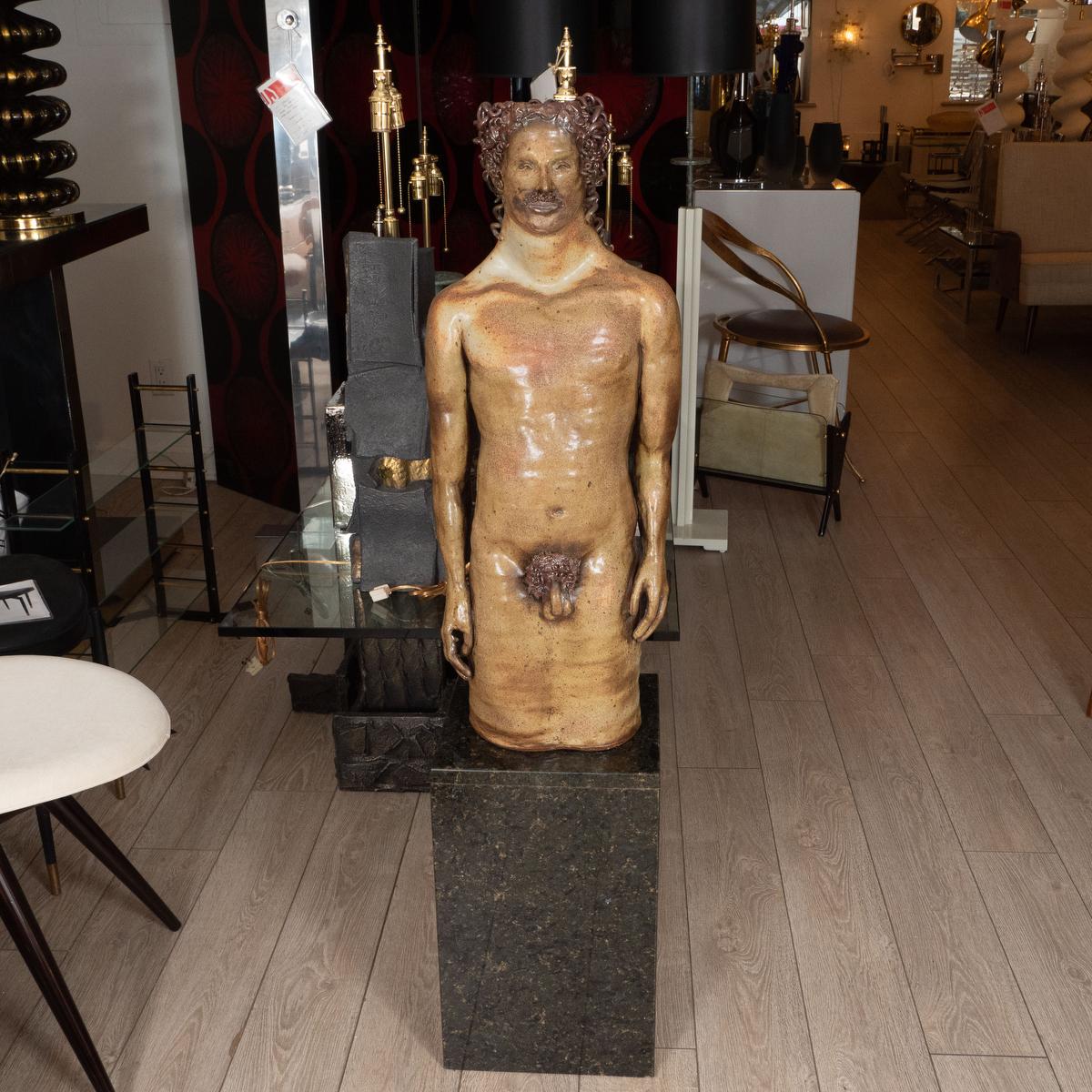Male nude terracotta sculpture on large marble base.