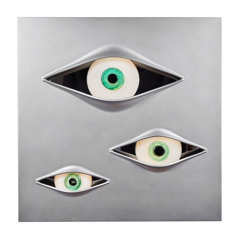 Luminous wall sculpture composed of a Sikablock panel, satin aluminum finish, customizable on request. The three eyes are made of crystal. Lighting provides LED light points at the eyes, and backlight LED on the wall box.