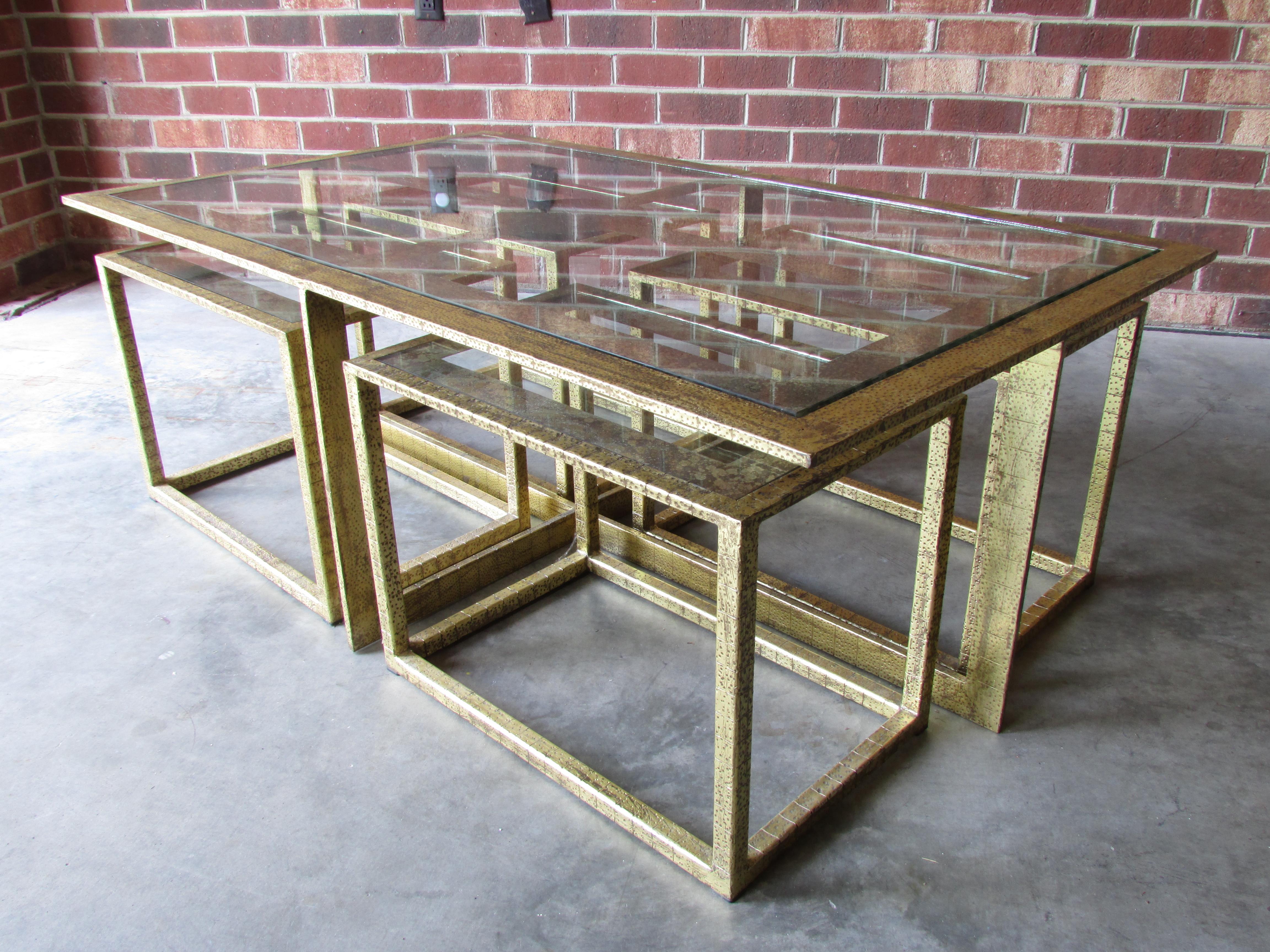 Beautiful coffee table with four smaller tables pushed underneath to bring out as needed metal frame is textured and has gold gilt finish and the inset glass is églomisé painted very much inspired by French 1940s furniture.