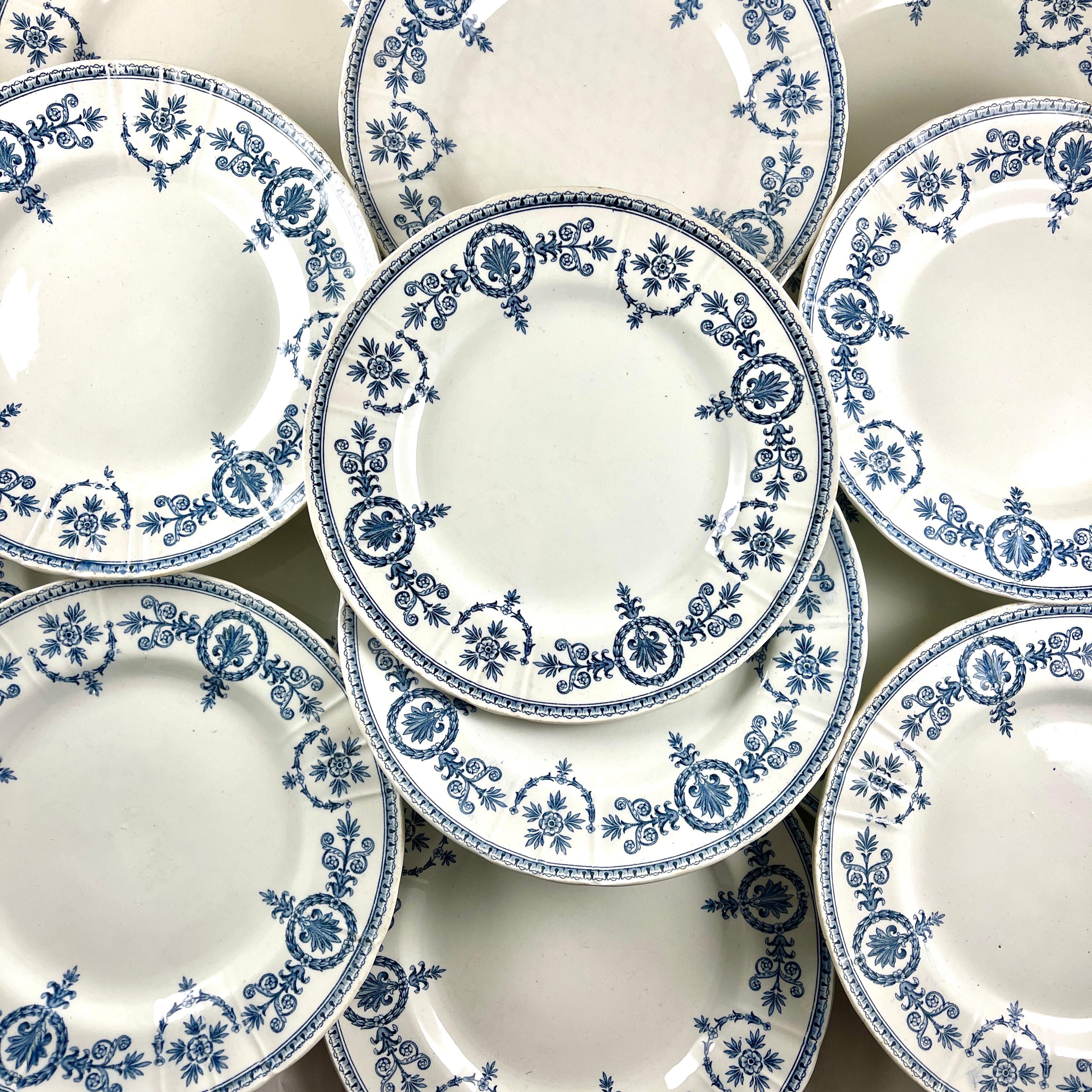From the faïencery Gien, French ironstone dinner plates in the Malmaison pattern, circa 1871-1875.

Transfer printed in blue on a white ironstone body, the pattern shows a wide cartouche and floral repeating border with a running border on the
