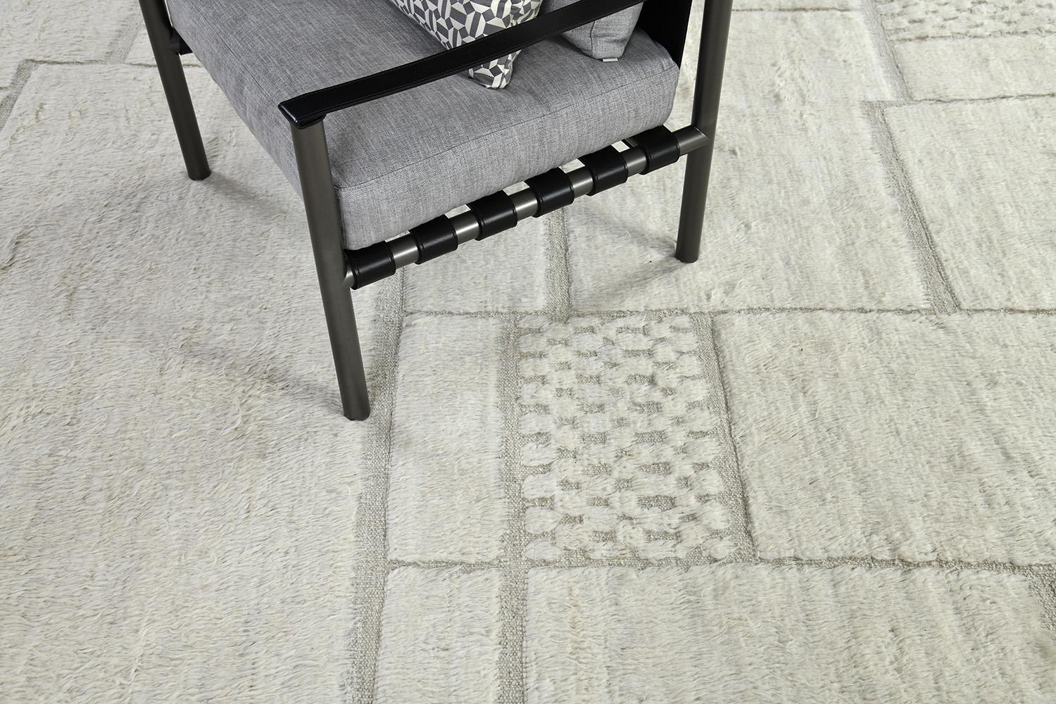 'Malmelah' is a beautiful textured rug with embossed detailing in checkered and rectangular shapes. Line work moving irregularly bring movement and are inspired by the Atlas Mountains in Morocco for the modern design world. The rug's bordering
