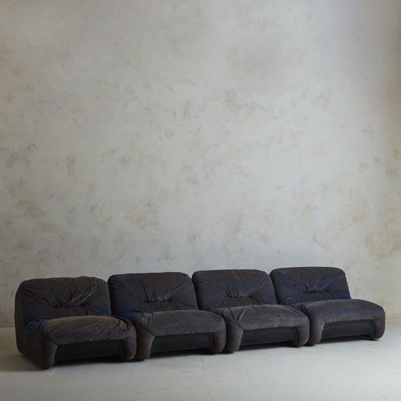 A set of French “Malu” modular lounge chairs designed by Claudio Vagnoni and Emilio Guarnacci in the 1970s. These stately chairs feature black acrylic shells and retain their original gray upholstery with ruched detailing. They sit slightly above
