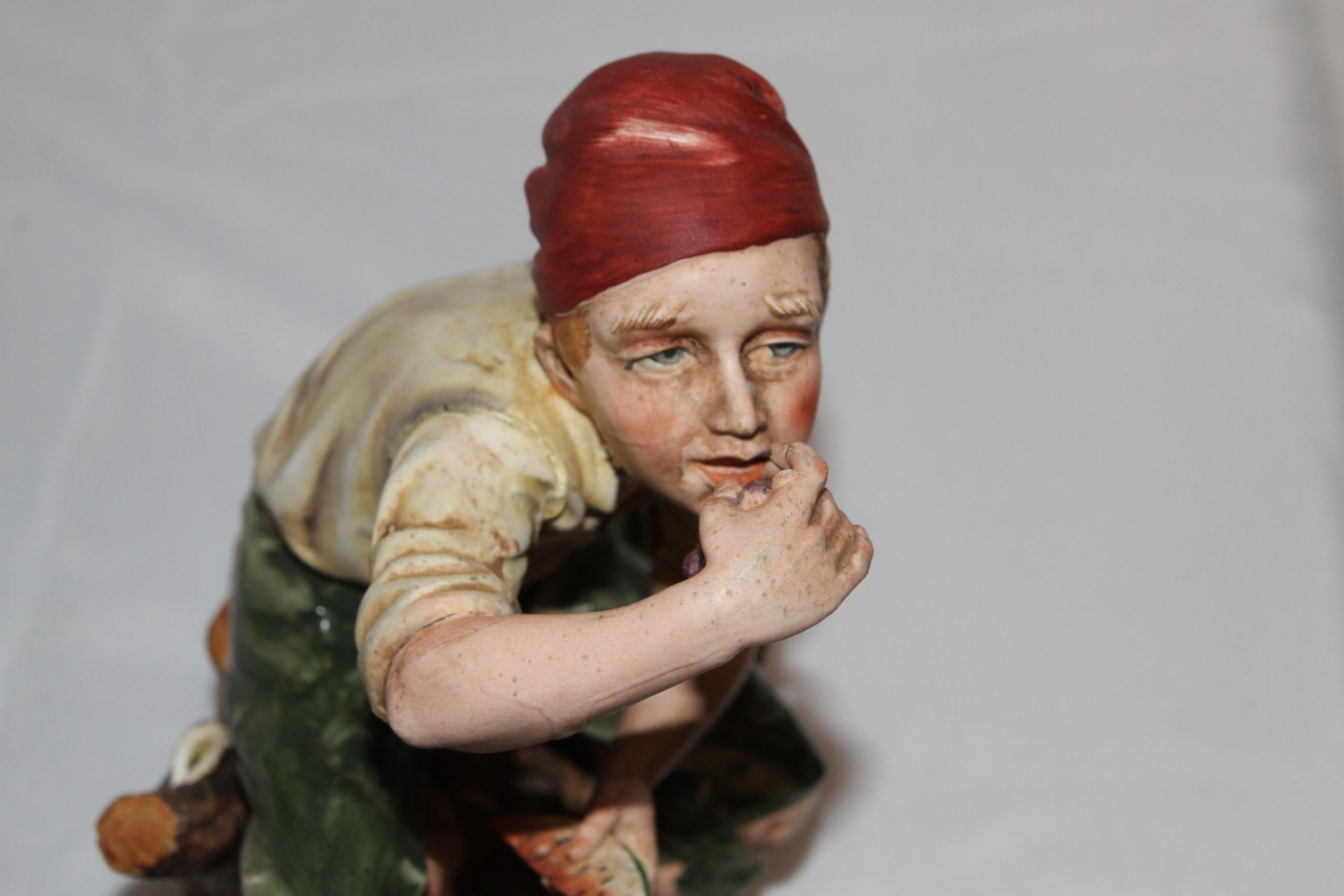 Piccola scultura di un uomo che mangia uva e anguria. Dipinto a mano.