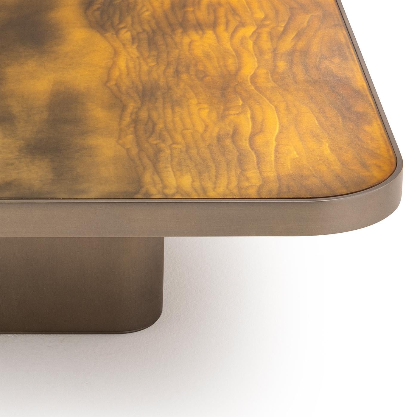 Presenting a coffee table of exquisite design, showcasing a Gargano-finished etched glass top. The base and outer edges are meticulously crafted from wood, lacquered to achieve a stunning brass color. This combination of materials results in a