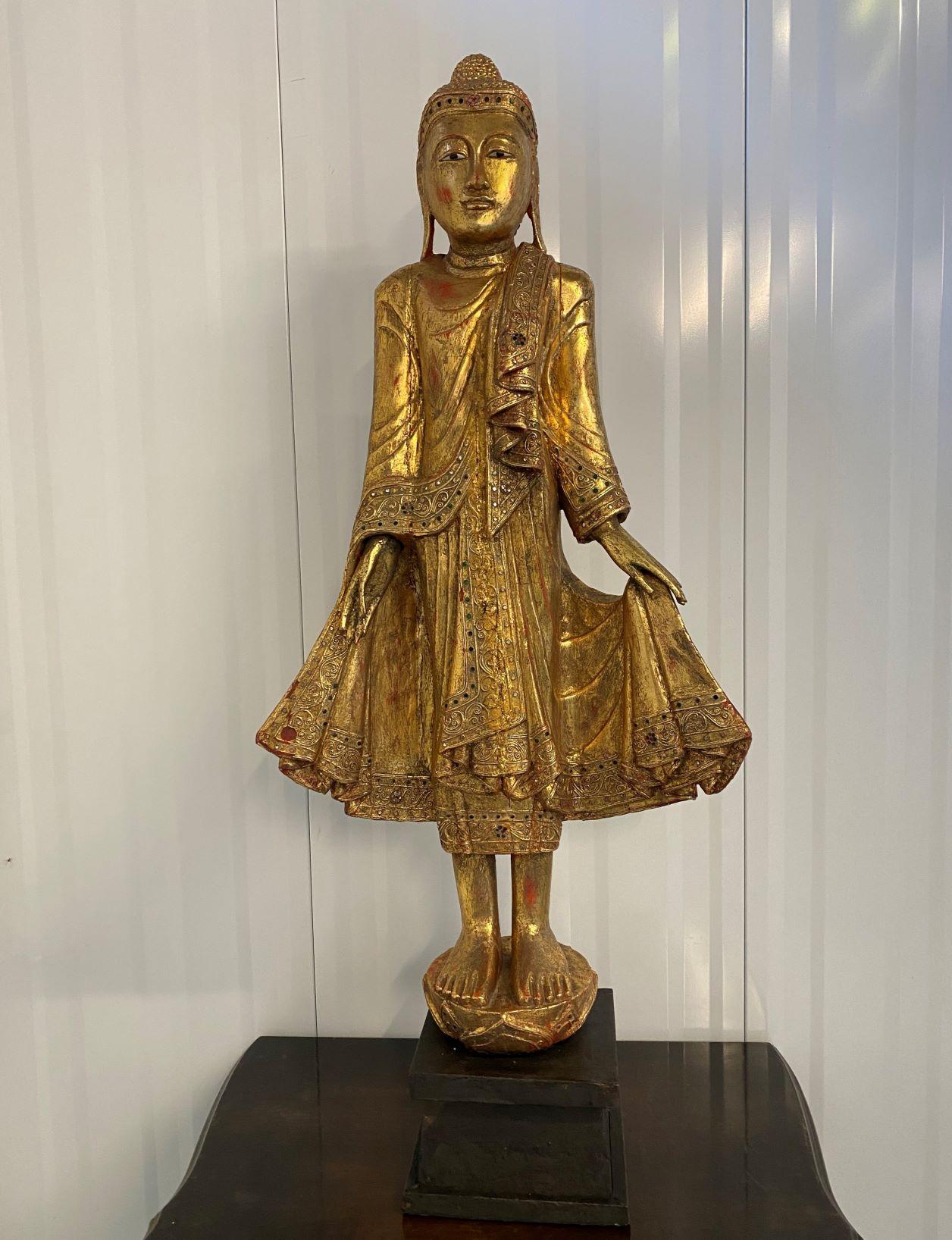 
Gorgeous hand-carved antique Burmese buddha statue with gilt finish, Burma, early 20th century.
This Buddha is depicted standing with hands poised in the teaching mudra, with meditative face, studded hair with rounded ushnisha, wearing sanghati