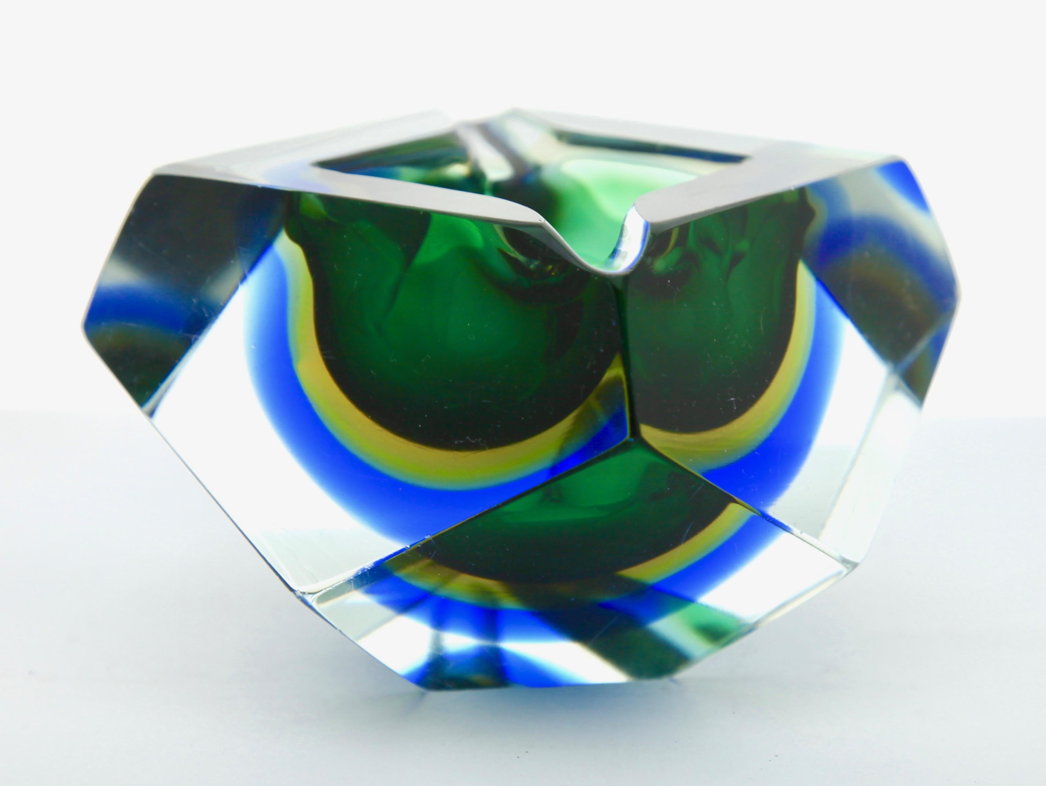 Attributed to Mandruzzato, this facetted block bowl with sectional cuts has a green core surrounded by amber and cobalt blue halos, bringing a dramatic contrast into your color scheme.
Still in lovely condition with only a few light scratches under