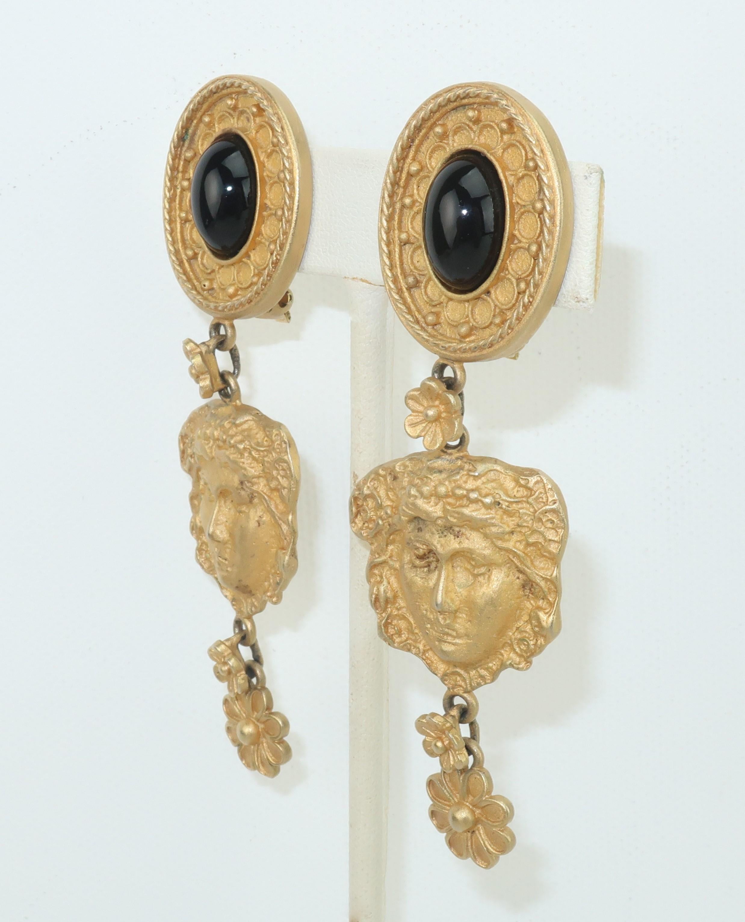 Mandy Dan brushed gold tone dangle earrings with an ancient Greek style design incorporating a Goddess and floral pattern.  The clip on base is accented with a black glass cabochon.  Signed at the back of each earring.
CONDITION
Good to fair