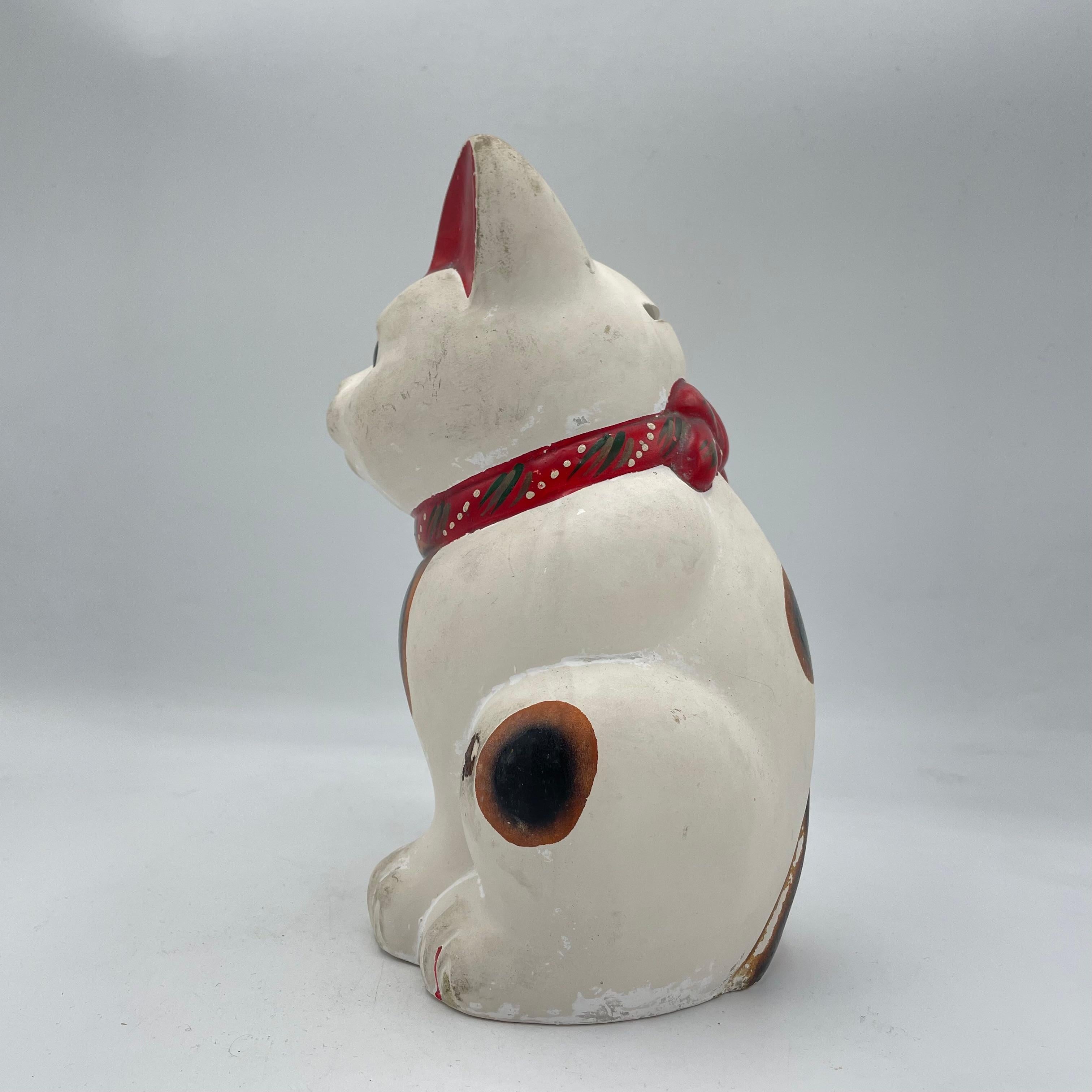 This is a vintage piggy bank of manekineko cat. It is made with Metal and it was made around 1960s in Showa era.

The maneki-neko is a common Japanese figurine which is often believed to bring good luck to the owner. In modern times, they are