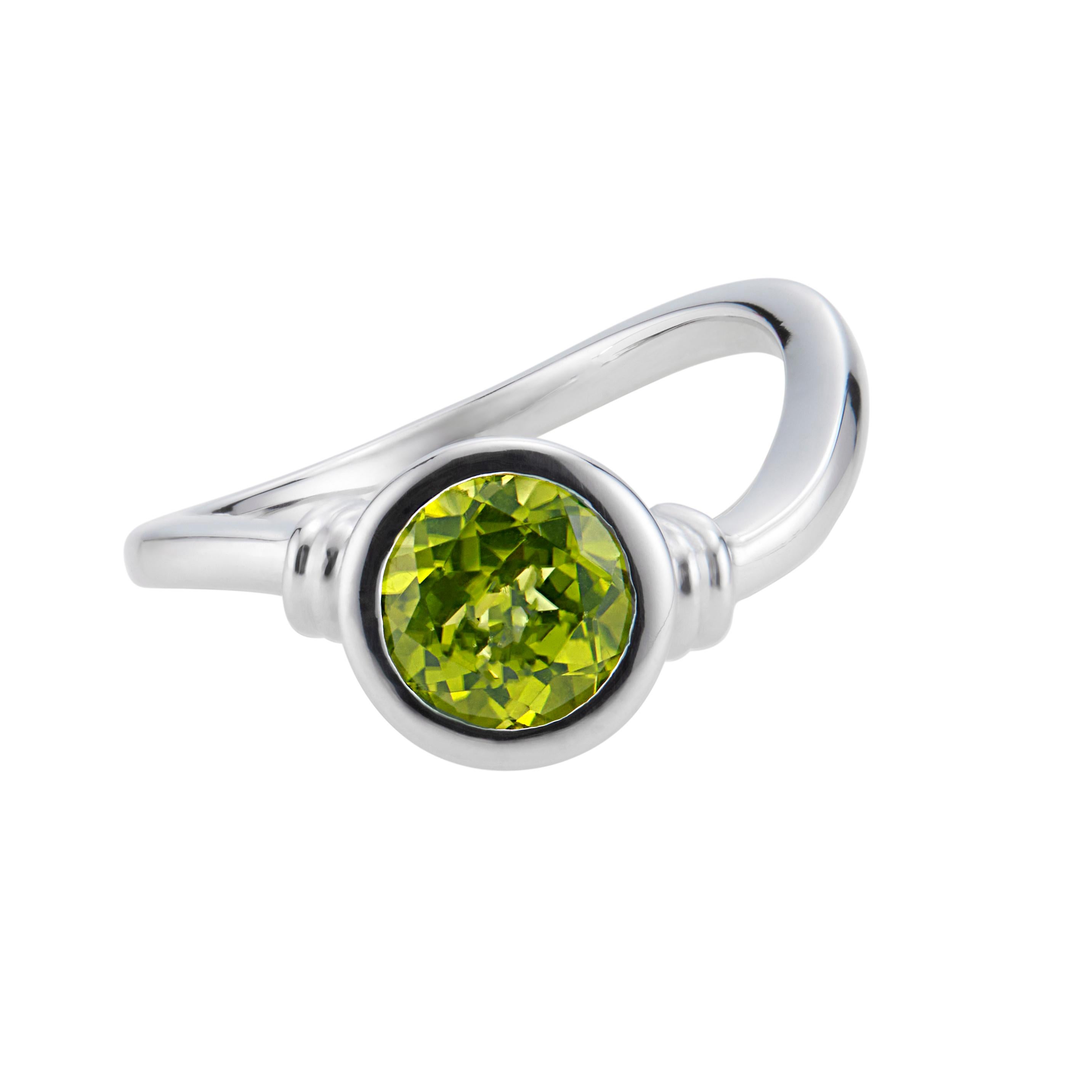 1.10 Carat round peridot engagement ring. 1 round bezel set peridot center stone in a 18k white gold setting by Manfredi of Greenwich, CT 

1 round green peridot, VS approx. 1.10cts
Size 7 and sizable 
18k white gold 
Stamped: 750
Hallmark: Manfredi