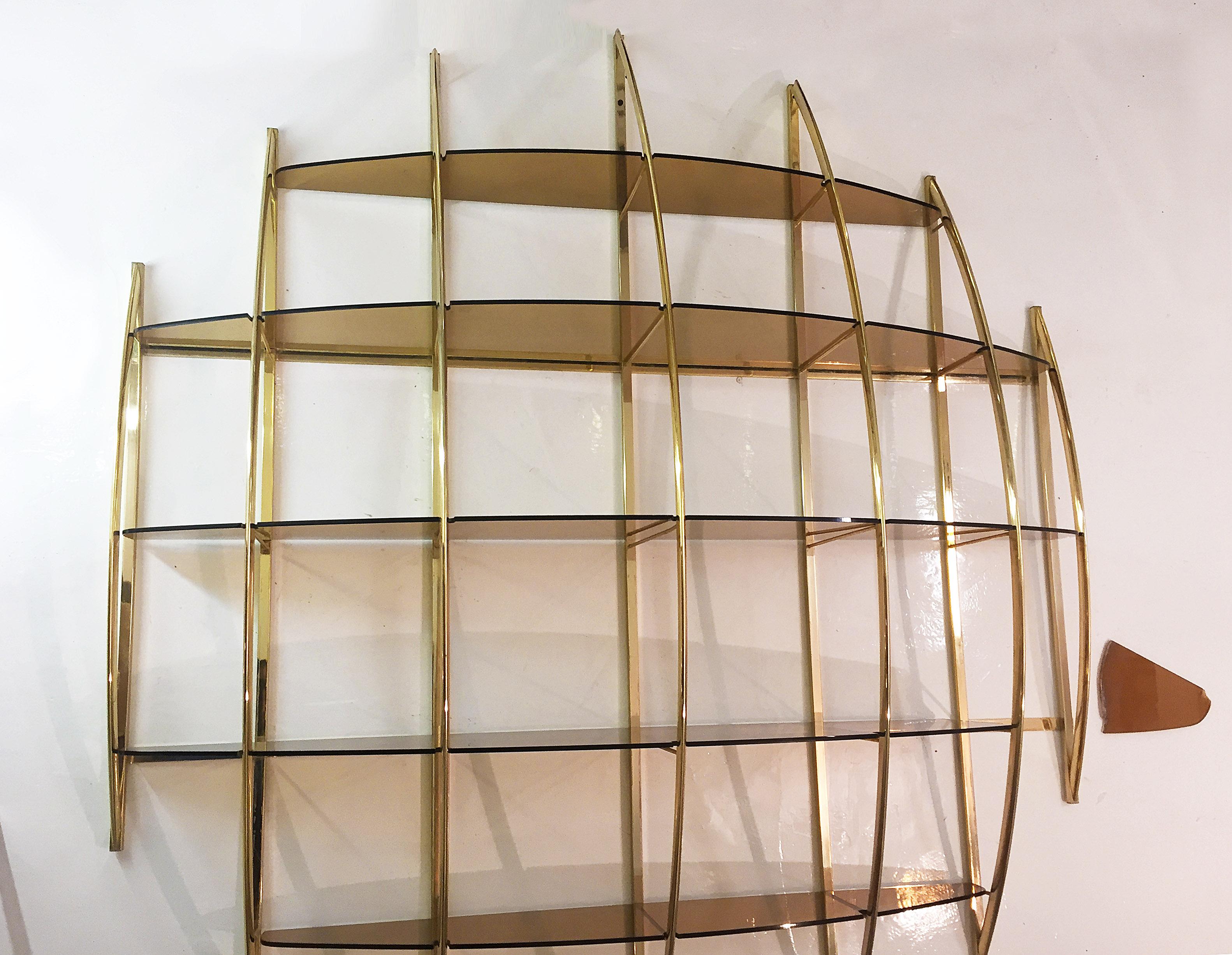 An extremely rare Manferdo Massironi brass semi-spherical shelving unit with interlocking smoked glass shelves. This piece by Massironi is usually and most commonly seen in wood or chrome, this is the first time we see it anywhere in brass! The
