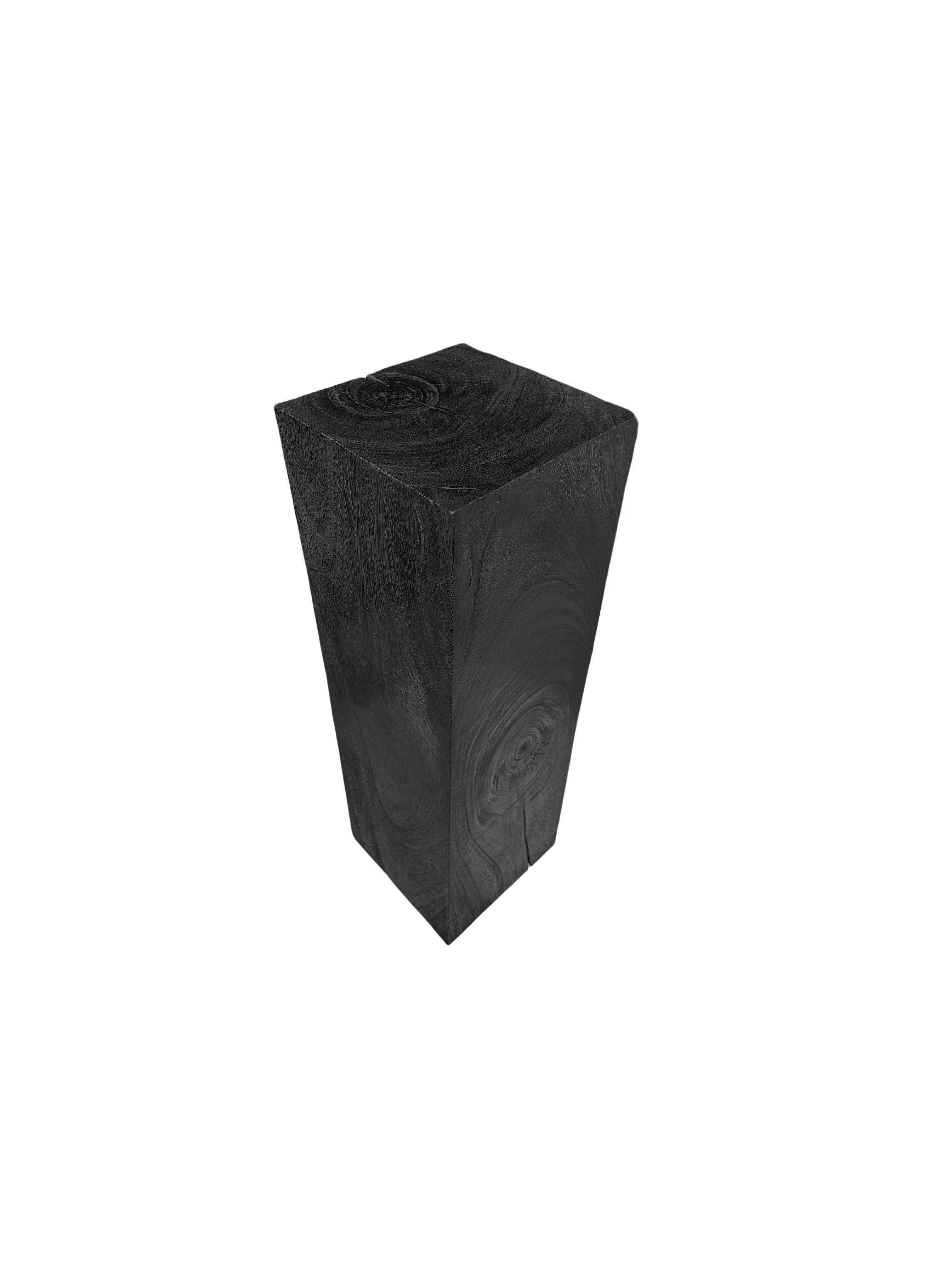 This striking mango wood pedestal features a bold burnt black finish that adds a contemporary edge to its natural charm. The rich, dark hue beautifully contrasts with the pedestal's stunning wood textures, showcasing the unique grain patterns and