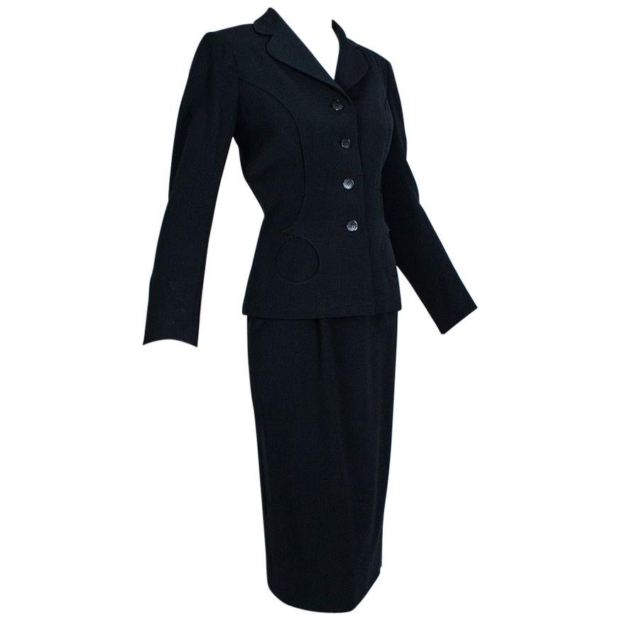 A Hindenburg survivor, Philip Mangone was born into a family of Italian tailors and favored the sleek, military silhouettes he employed while designing WAC uniforms during WWII. With its strong shoulders and slim skirt, this suit is demonstrative of