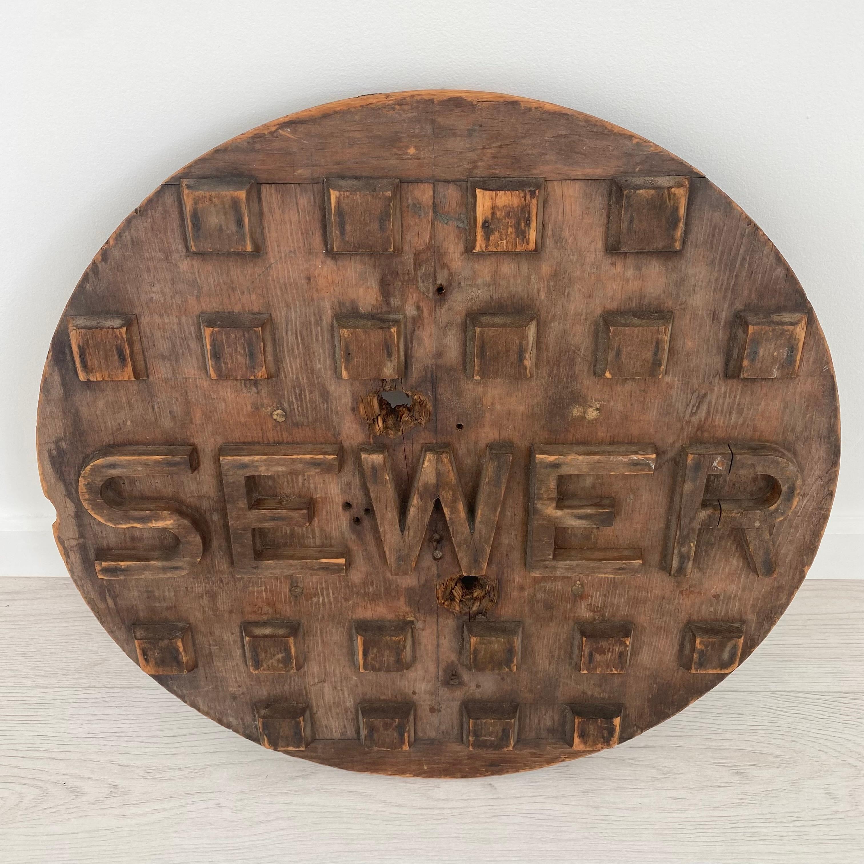 Extremely unique wooden sewer cap prototype. Made by by various wooden cubes and blocks as well as letters nailed to the front of the main ply of the cap giving it its design. The base has some crossbars also made of wood which can be used for