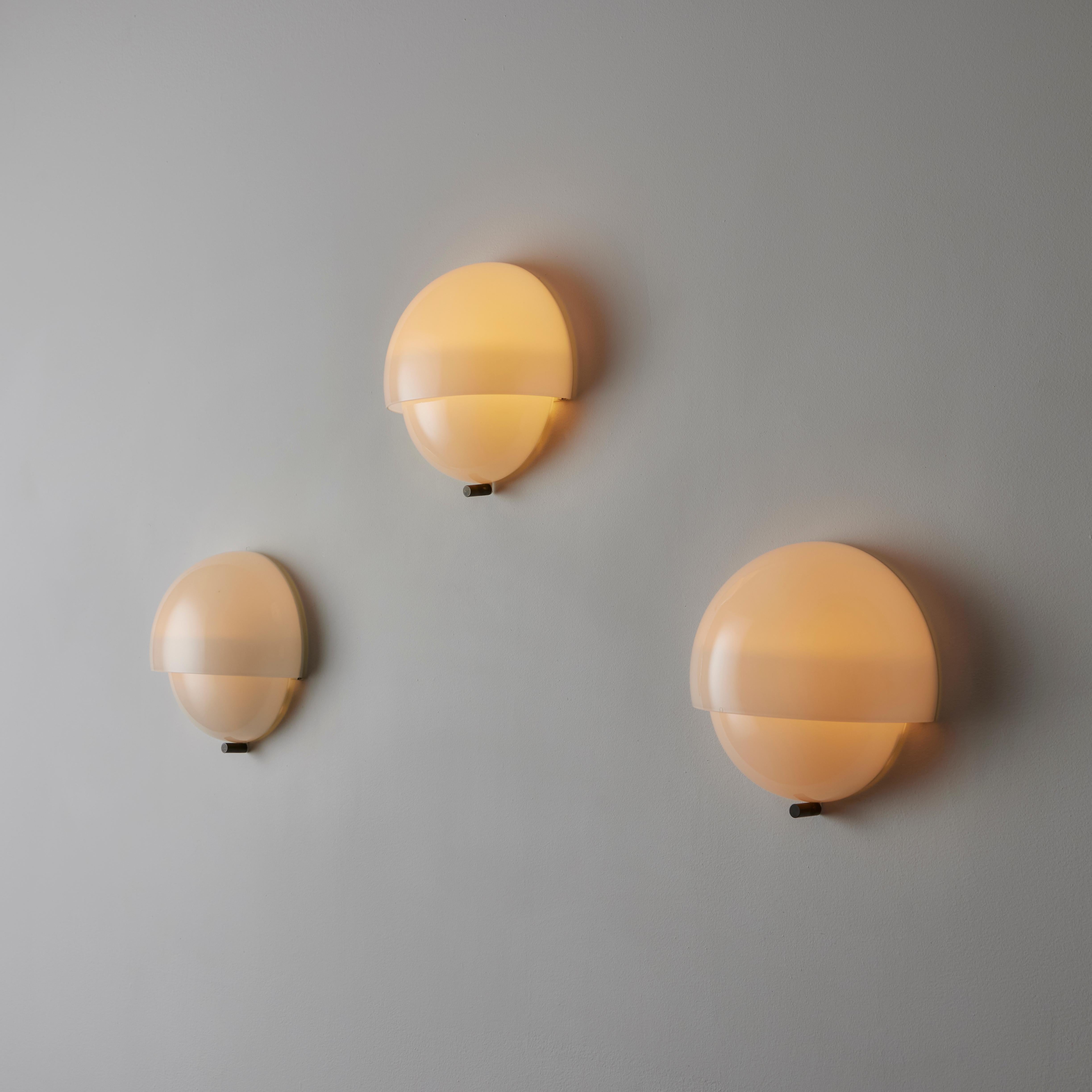 Mania Sconces by Vico Magistretti for Artemide. Designed and manufactured in Italy, circa 1960. Minimal half layered half sphere sconce made from delicate opaline glass. Each sconce holds two E14 socket types, adapted for the US. We recommend using