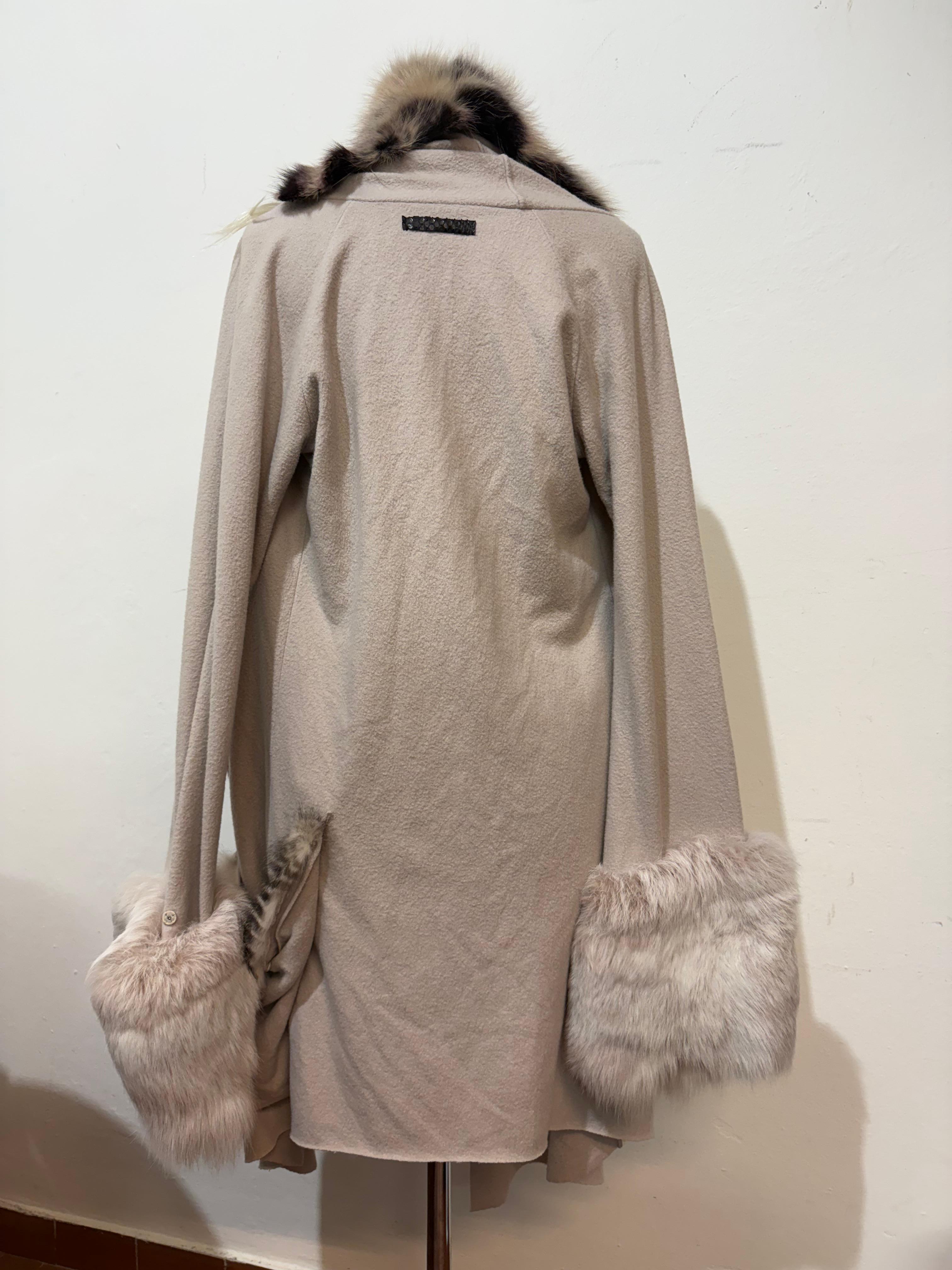 Magnifique manteau par Maniac Coates
Coton (60%), cachemire (25%), textile mélangé
Fourrure de vison et de lapin
Toute la fourrure est amovible (boutons automatiques)
Couleur gris clair
Deux poches 
Longueur épaule/hémoire cm 106 (41.7