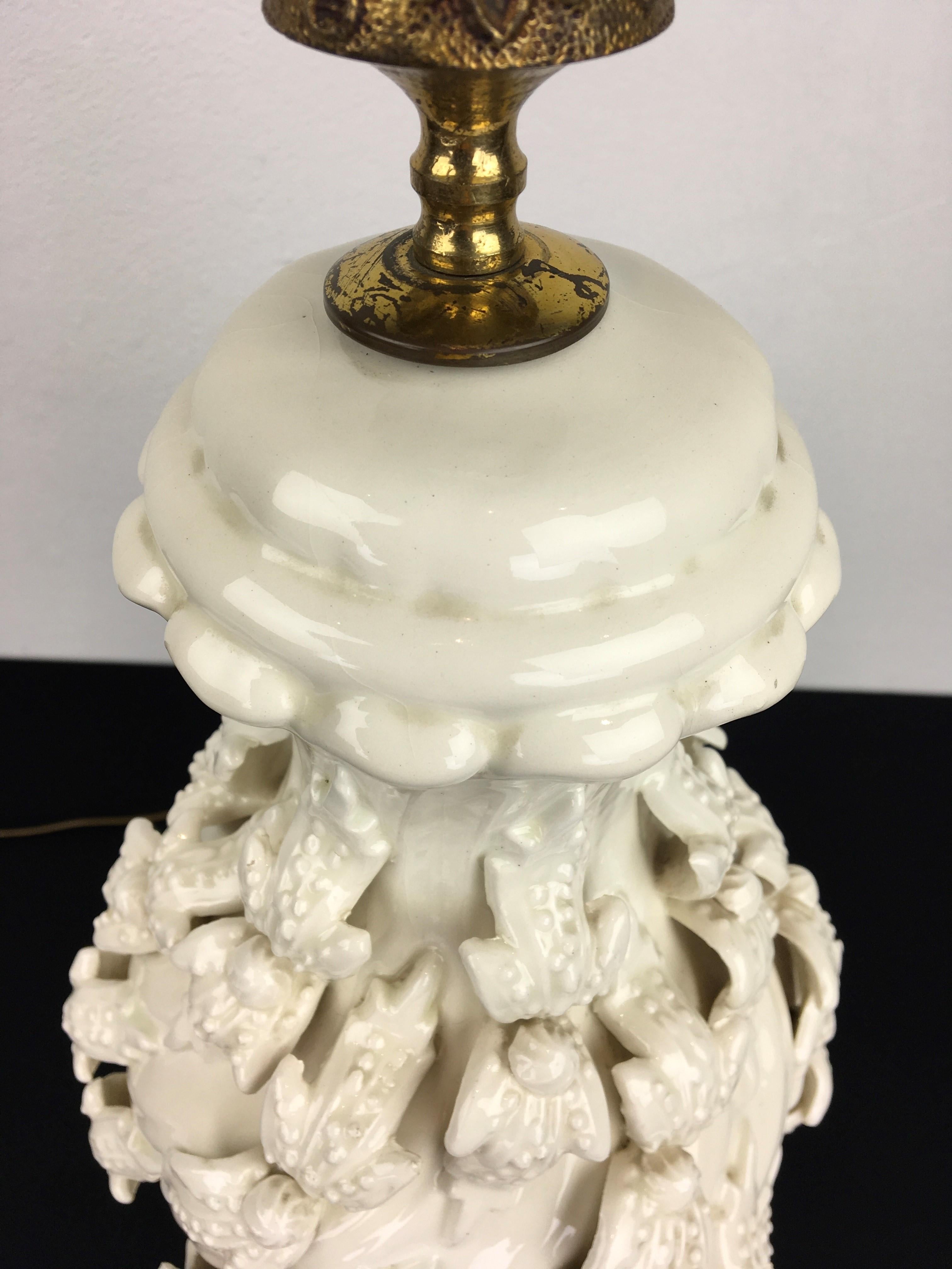 Spanish white manises ceramic table lamp with flowers. 
This white table lamp has beautiful flowers all around and is mounted on a gilded wooden base.
A white glazed sculptural ceramic table light from the 1960s, which will look very stylish in