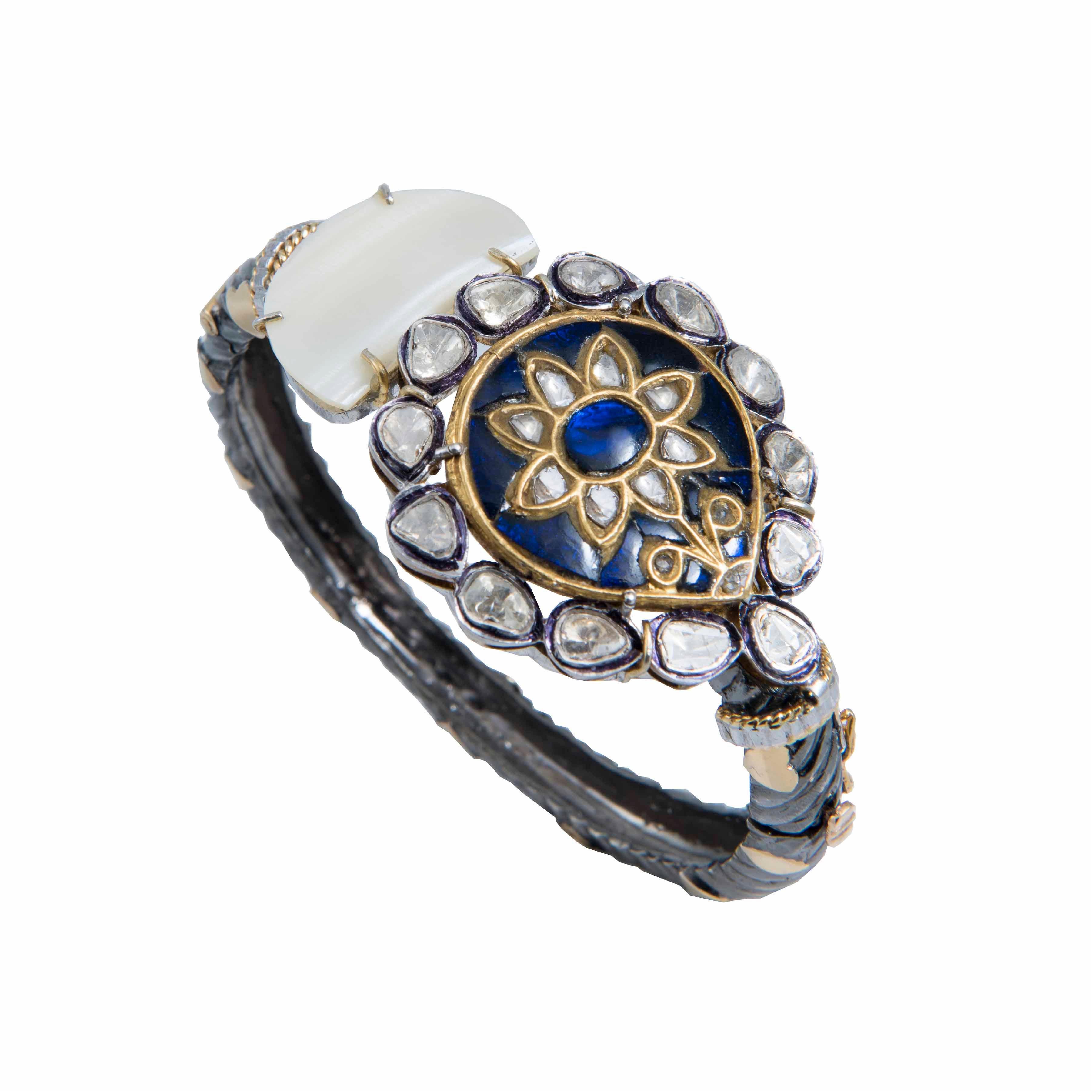 This limited edition bracelet from Iconic series of the brand, showcases a flirty interplay of black chrome plated pure silver band with 18k gold work on it, and a handcrafted blue iolite petal motif embellished with polkis (uncut diamonds) on the