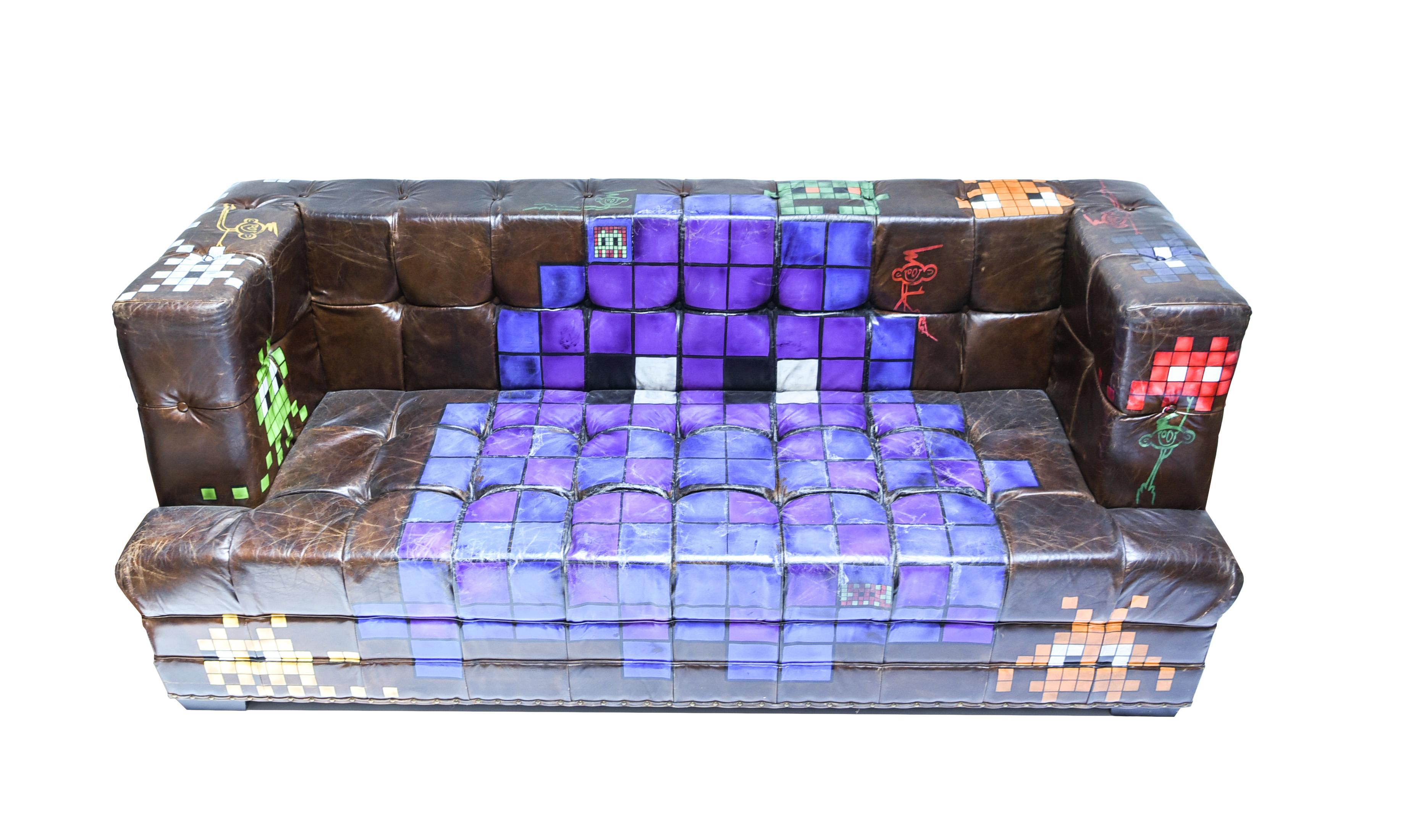 This is a very interesting sofa in the manner of the Graffiti artist Invader. A tag on the bottom of the sofa dates it to 2014. As the paint is well adhered to the sofa, it retains its function as seating while doubling as a piece of art in and of