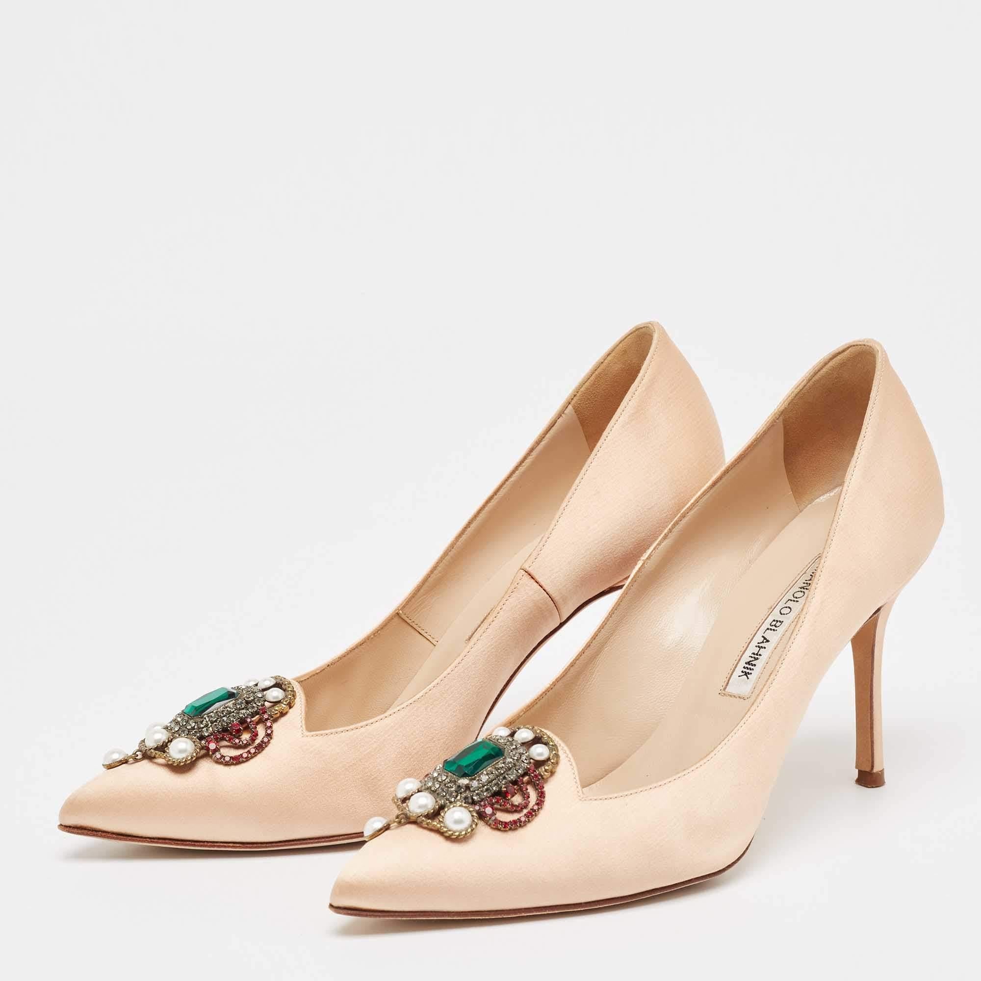 Effortlessly slip into this beautiful pair of pumps from the makers of Manolo Blahnik. They have been crafted from luxurious satin and carry a classic shade of beige. They have been adorned with pearl embellishments on the uppers. The 9.5cm heels