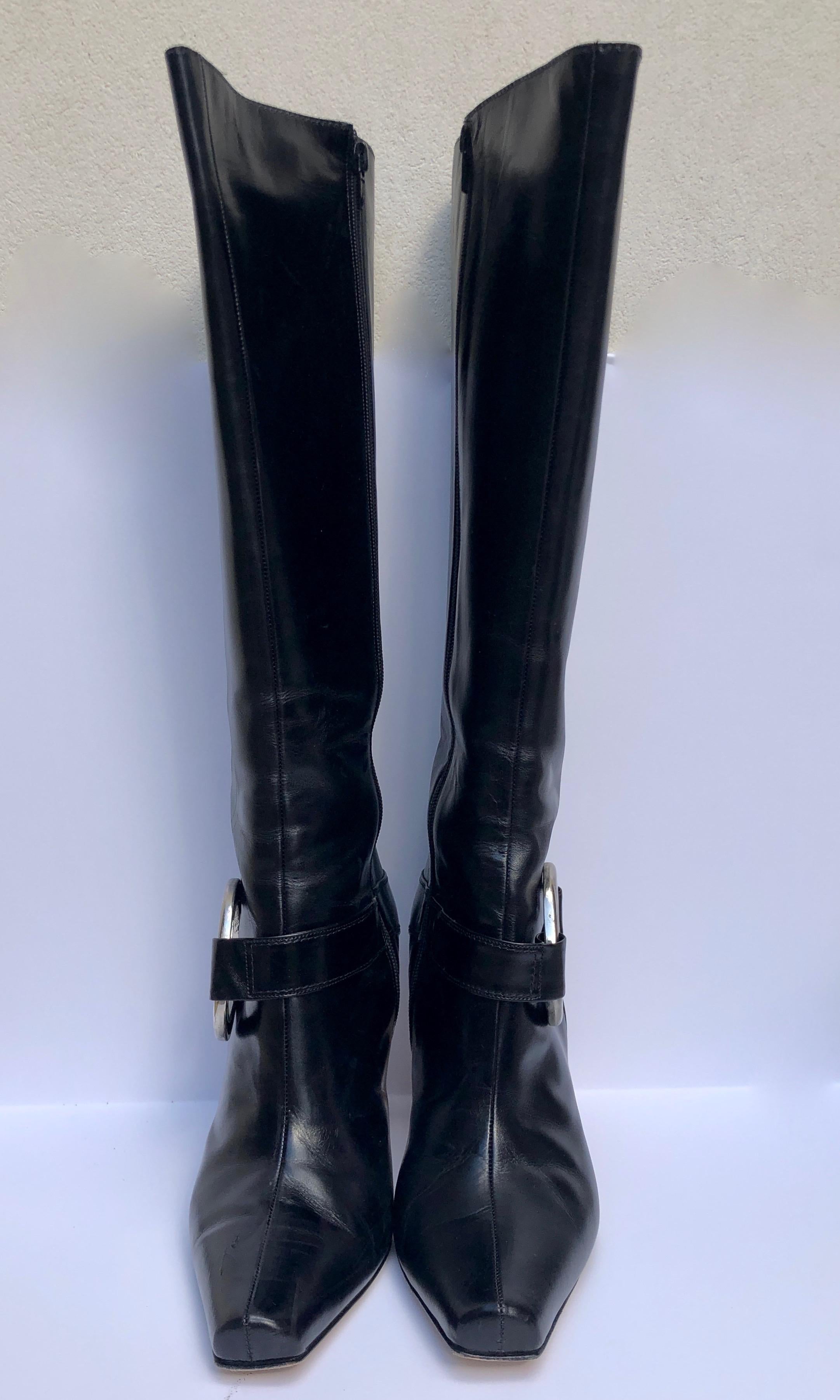 Make:  Manolo Blahnik (Literally signed on the sole of the boot.)
Place of Manufacture:  Italy
Size:  40 EU /  10 US
Materials:  Leather and metal
Color: Black with silver medallion and black leather harness
Style:  Black knee boot with interior