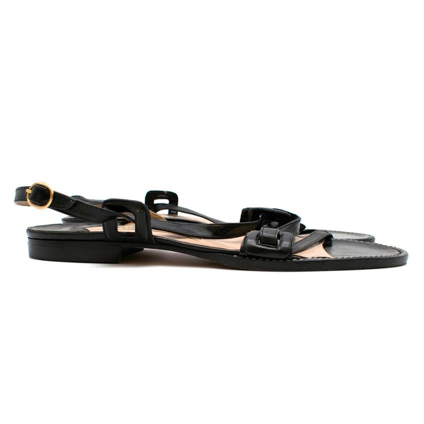Manolo Blahnik Black Leather Slingback Flat Sandals 

- Black leather 
- Crossover strap design 
- Buckle fasten 

Made in Italy

Please note, these items are pre-owned and may show signs of being stored even when unworn and unused. This is