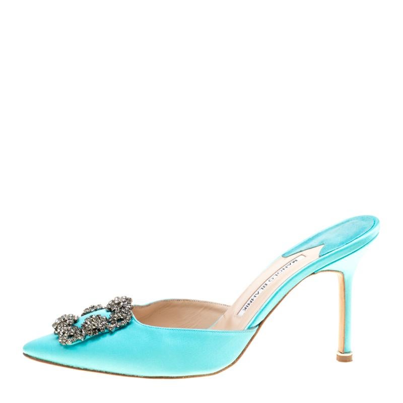 Walk with grace and confidence in these cyan blue Hangisi mules by Manolo Blahnik. Shining bright with a pointed toe that is elevated with a gunmetal-tone crystal embellished brooch, leather lining, comfortable insole and a 9.5 cm heel, this satin