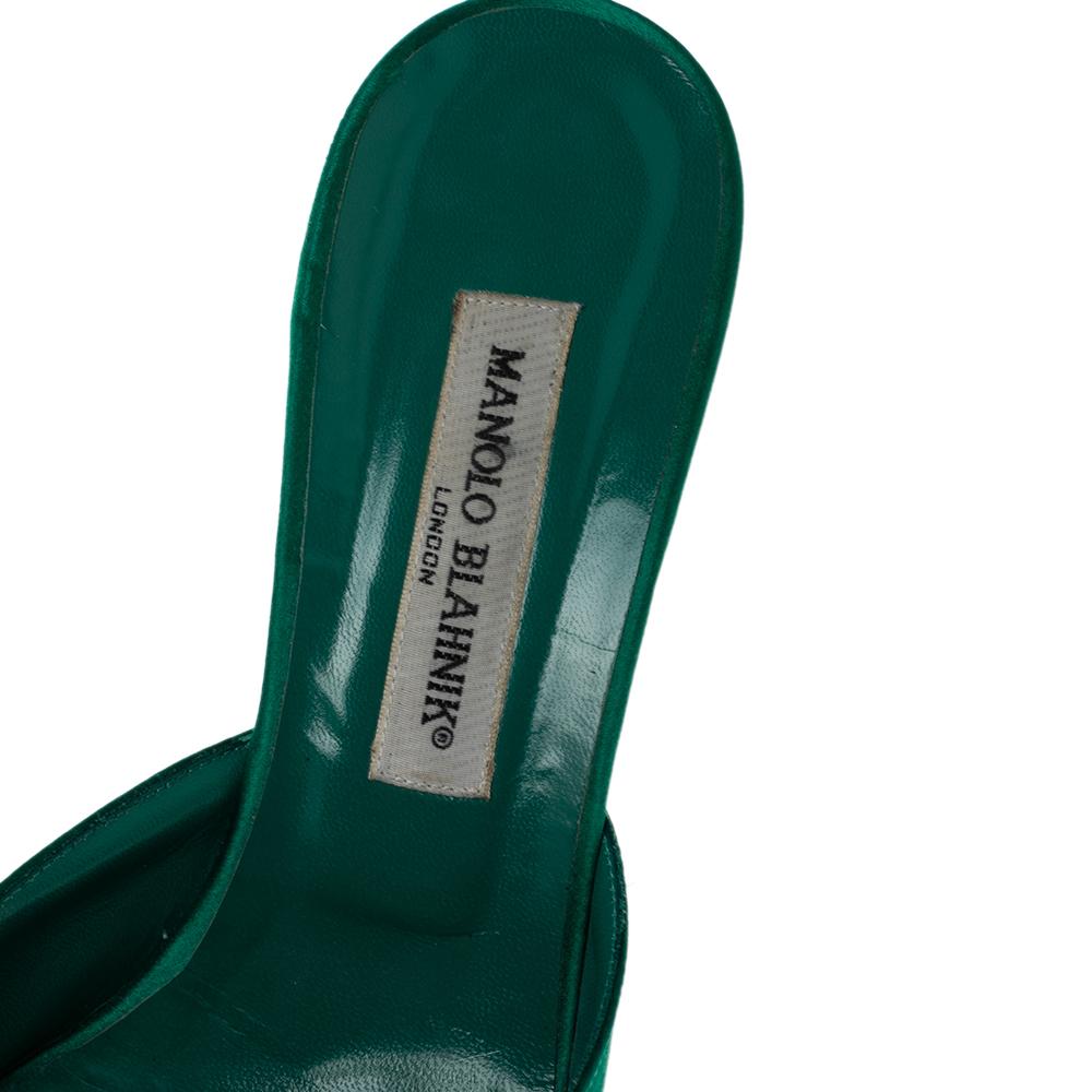 Walk with grace and confidence in these green Hangisi mules by Manolo Blahnik. Featuring an embellished brooch on the pointed toes, leather lining on the insoles, and 9.5 cm heels, this satin pair will never fail to elevate the charm of your