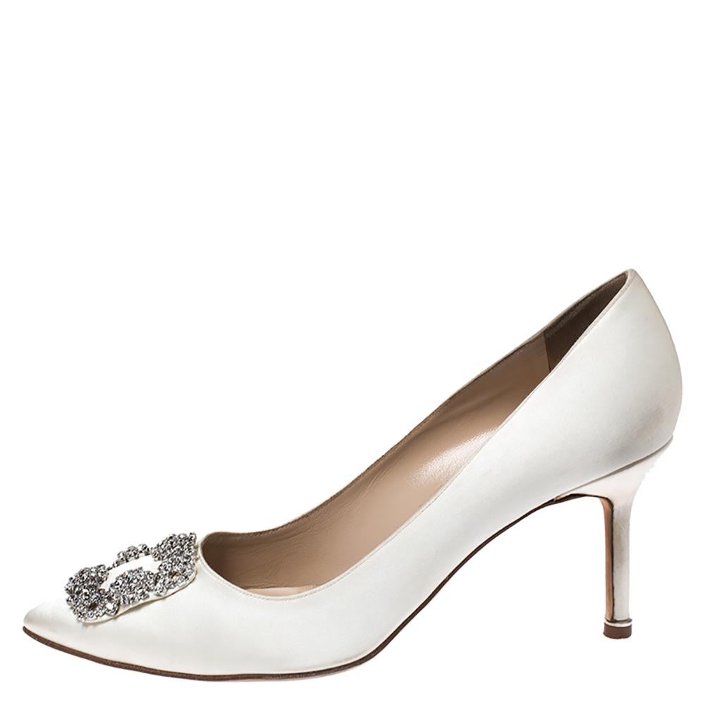 Walk with grace and confidence in these pumps by Manolo Blahnik. Styled in ivory, with dazzling crystal embellishments on the pointed toes, and leather insoles to provide comfort, these satin Hangisi pumps will never fail to lift your outfits.