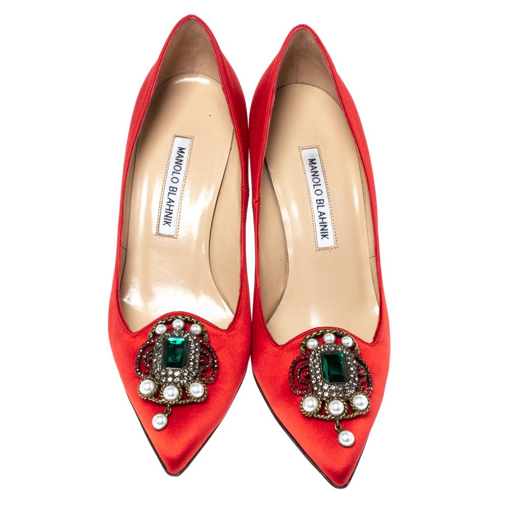Walk with grace and confidence in these red pumps by Manolo Blahnik. Flaunting contemporary fashion with pointed toes which are enhanced with a crystal embellished brooch at the vamps, leather lining, comfortable insole, and 9 cm heels, this
