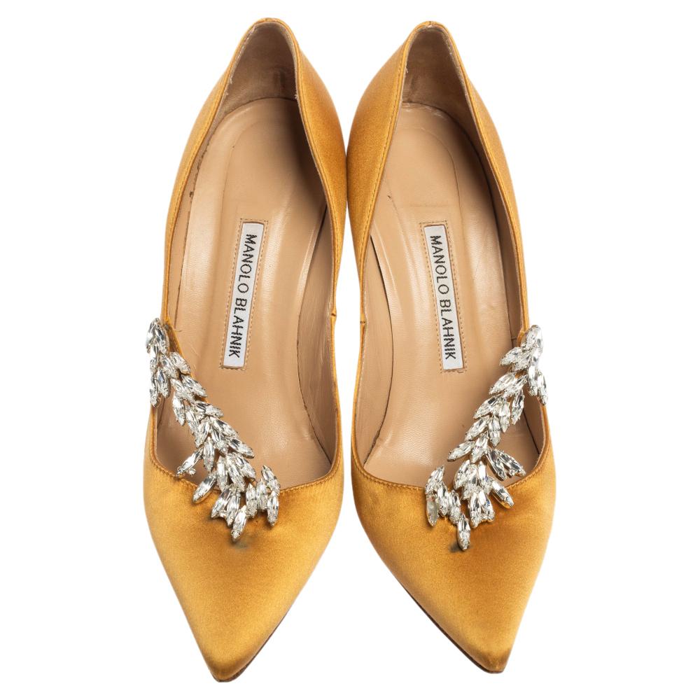 Allow this sumptuous pair of pumps by Manolo Blahnik to blow your look. Crafted with satin, they are adorned with eye-catching embellishments and profile adorable pointed toes. The leather-lined insoles carry brand labeling. This pair is elevated on