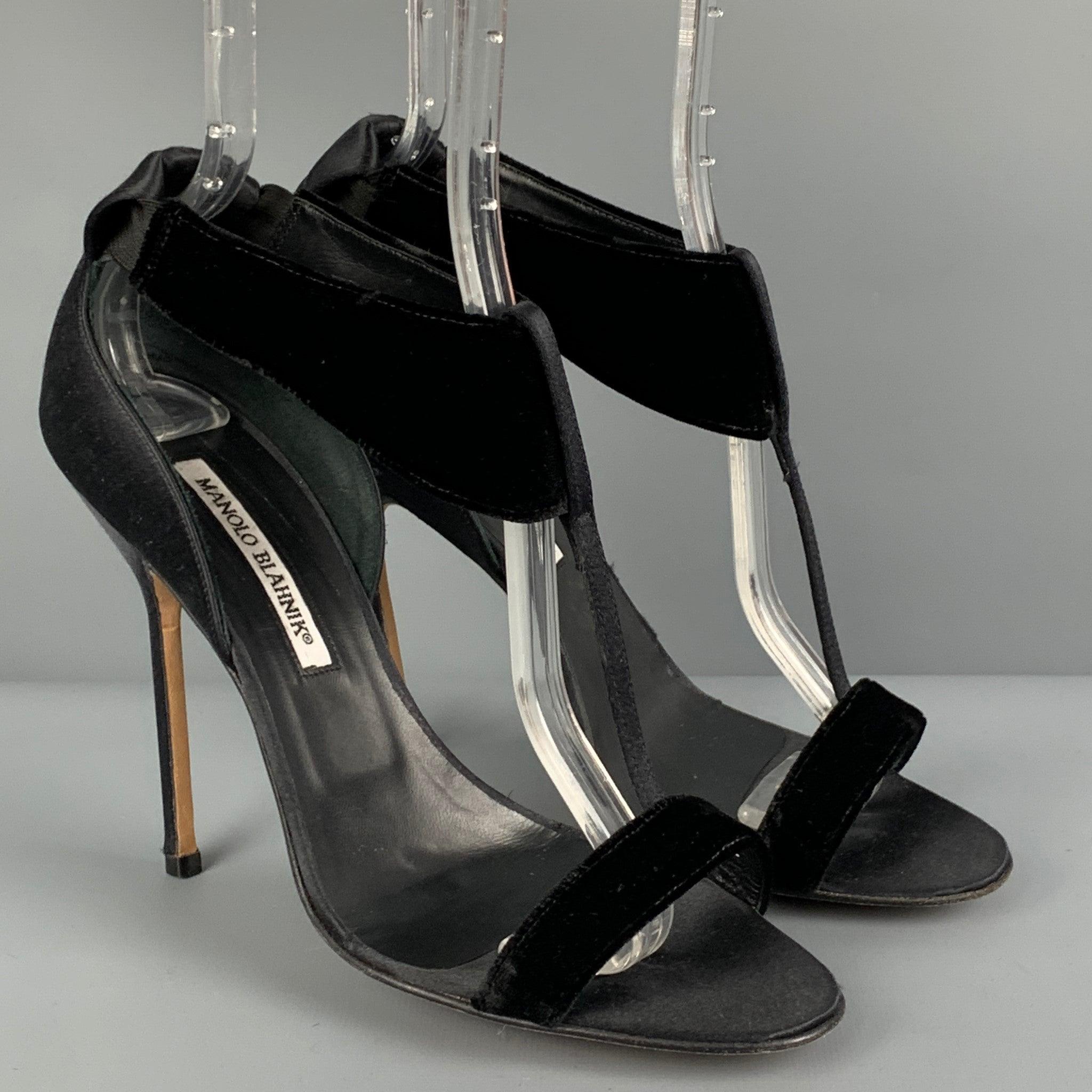 MANOLO BLAHNIK sandals comes in a black satin with a velvet trim featuring a t-strap style, open toe, and a stiletto heel. Made in Italy.
Very Good
Pre-Owned Condition. 

Marked:   39 

Measurements: 
  Heel: 4.5 inches 
  
  
 
Reference: