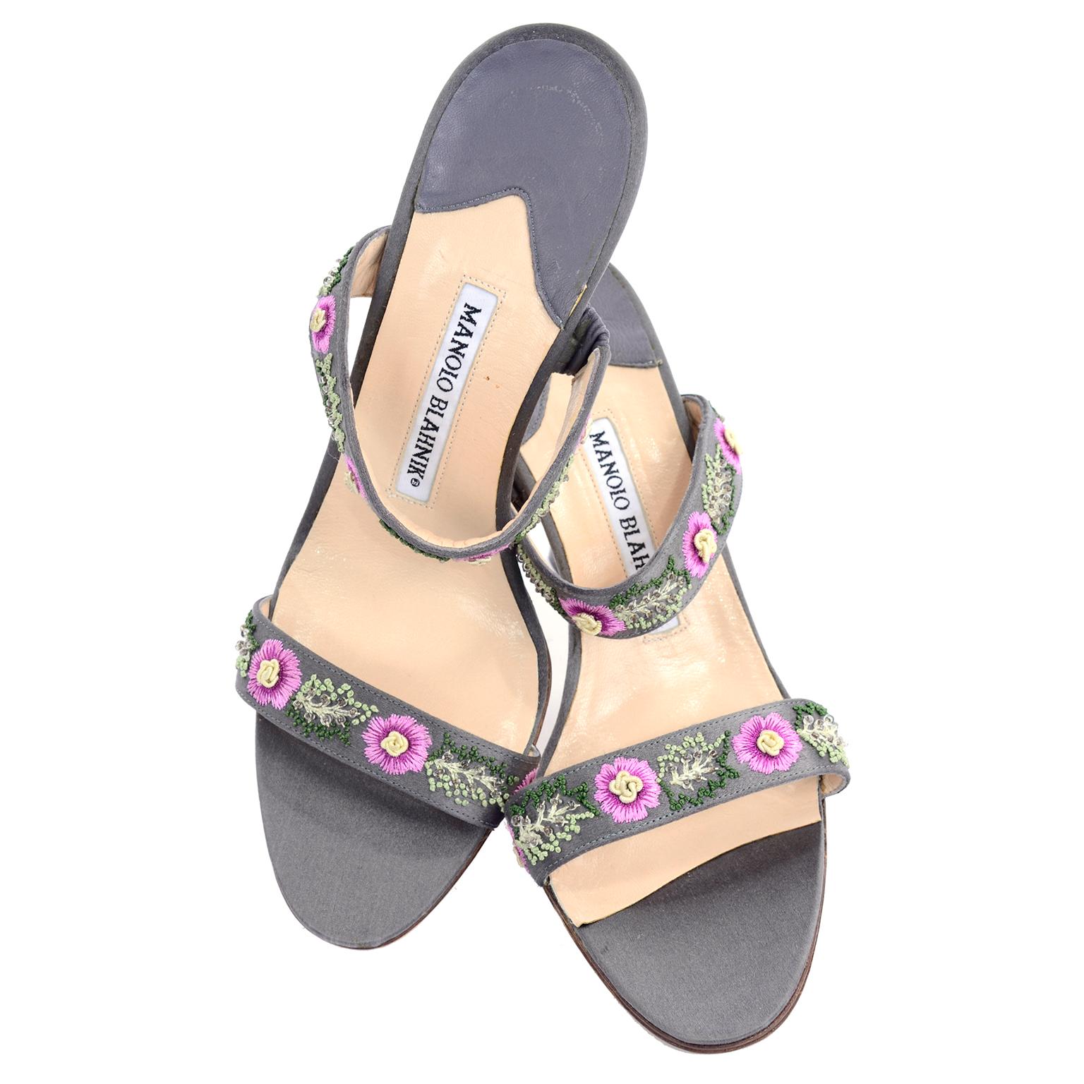 Diese hübschen grauen Manolo Blahnik Schuhe haben wunderschöne gestickte rosa Blumen mit cremefarbener Mitte und gestickte grüne Blätter, die mit Perlen verziert sind.  Diese zehenoffenen Slide-Sandalen haben schöne Absätze und wurden nur einmal