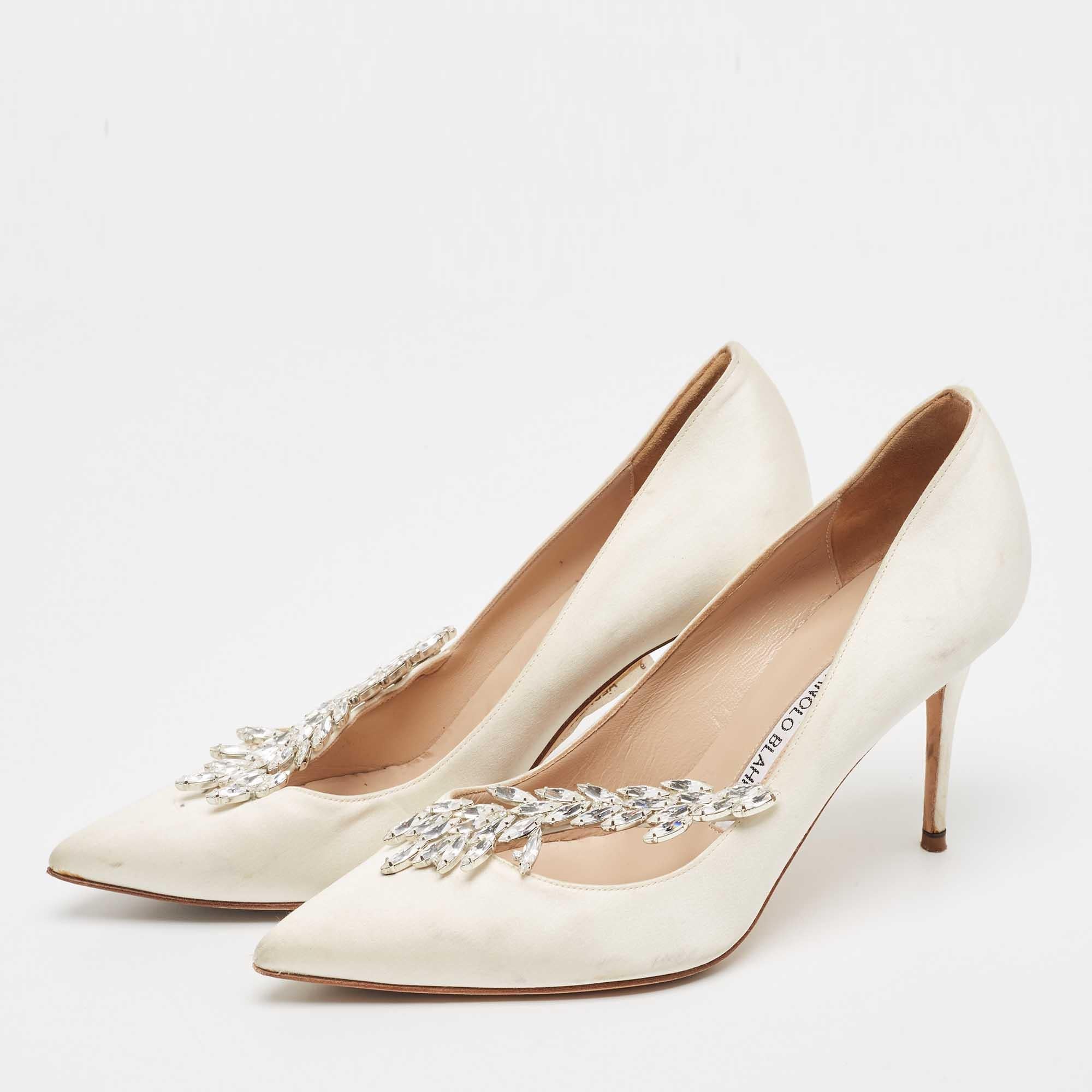 Allow this grand pair of pumps by Manolo Blahnik to elevate your look. Crafted with satin, they are adorned with eye-catching Nadira embellishments and profiles pointed toes. The leather-lined insoles carry brand labeling. This pair is elevated on
