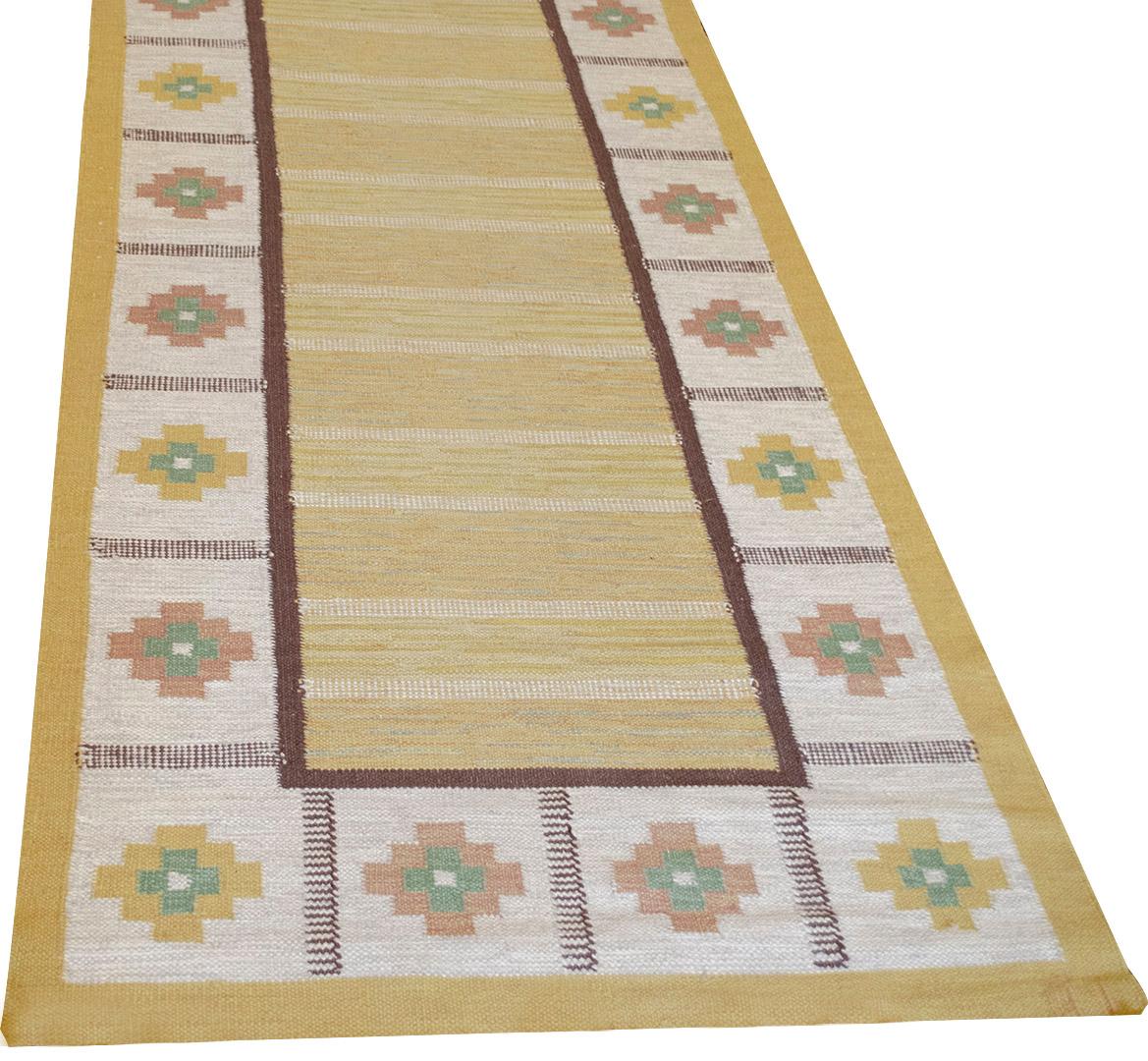 This traditional handwoven Swedish rug has a yellow field enclosed in a thin brown rectangle surrounded by an ivory field of alternating brown and yellow lozenges with an outer yellow border. An excellent example of Swedish weaving.
   