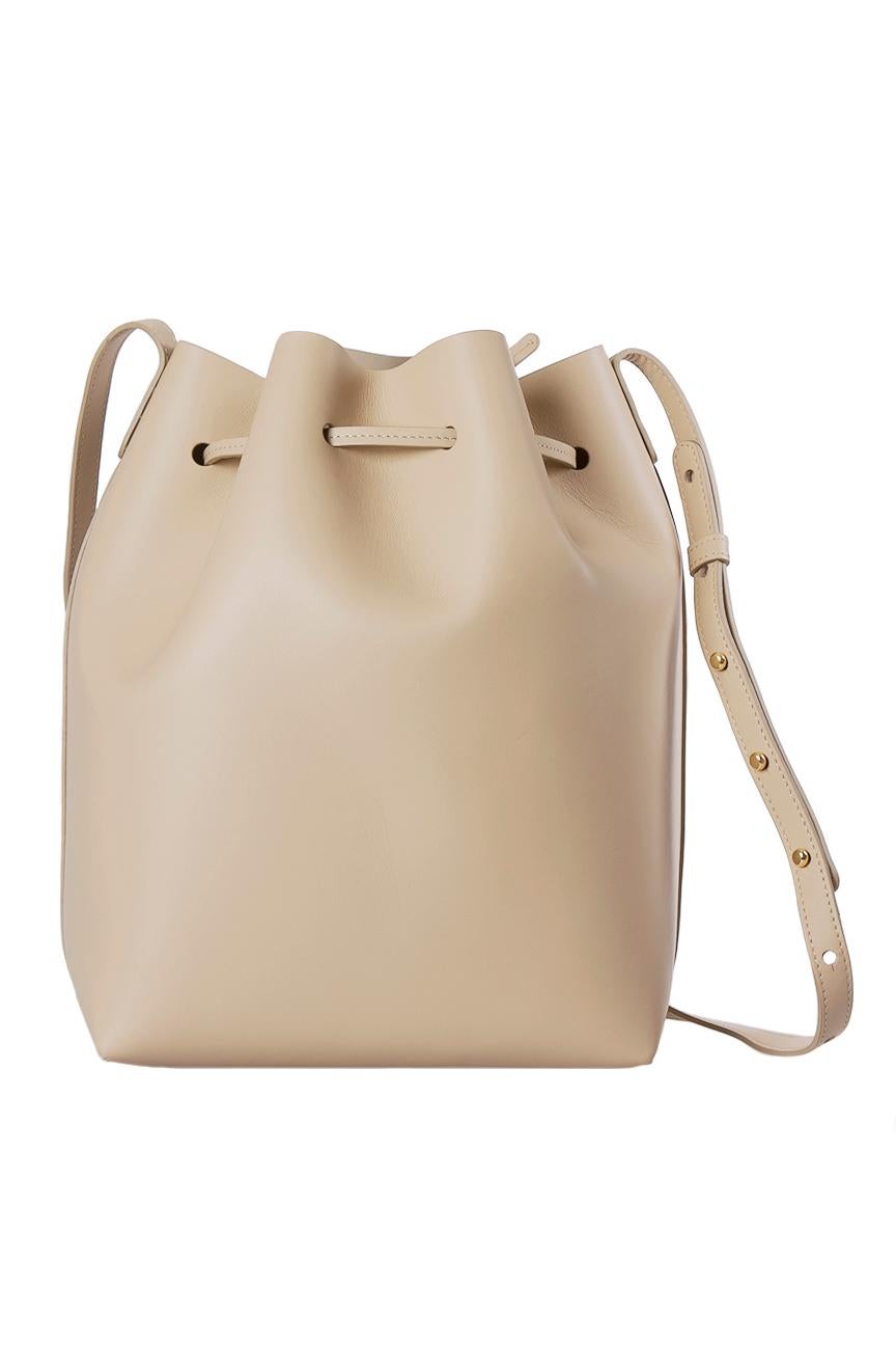 This Mansur Gavriel piece, crafted from beige leather is an excellent addition to go with your sophisticated getup for any well-off event. This Bucket bag is characterized by a drawstring closure that secures a well-sized interior accompanied with a