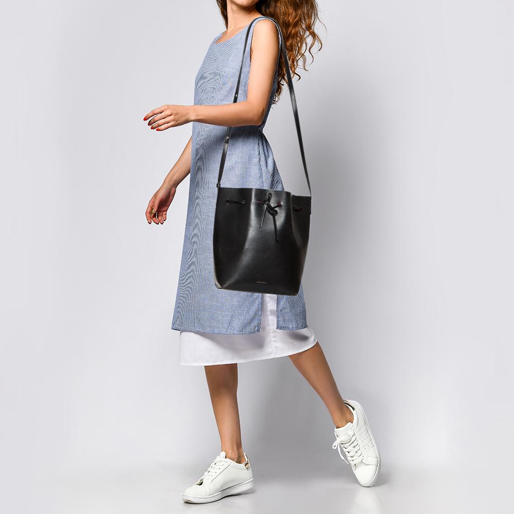 This wonderful Mansur Gavriel design is made from leather. The bag has a bucket shape with a drawstring closure that secures the leather interior. It is complete with a shoulder strap. Black in shade, it is an apt accessory to carry your everyday