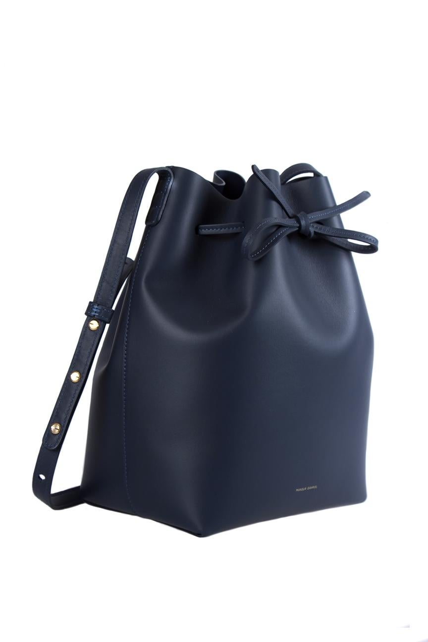 This Mansur Gavriel piece, crafted from navy blue leather is an excellent addition to go with your sophisticated getup for any well-off event. This Bucket bag is characterized by a drawstring closure that secures a well-sized interior accompanied